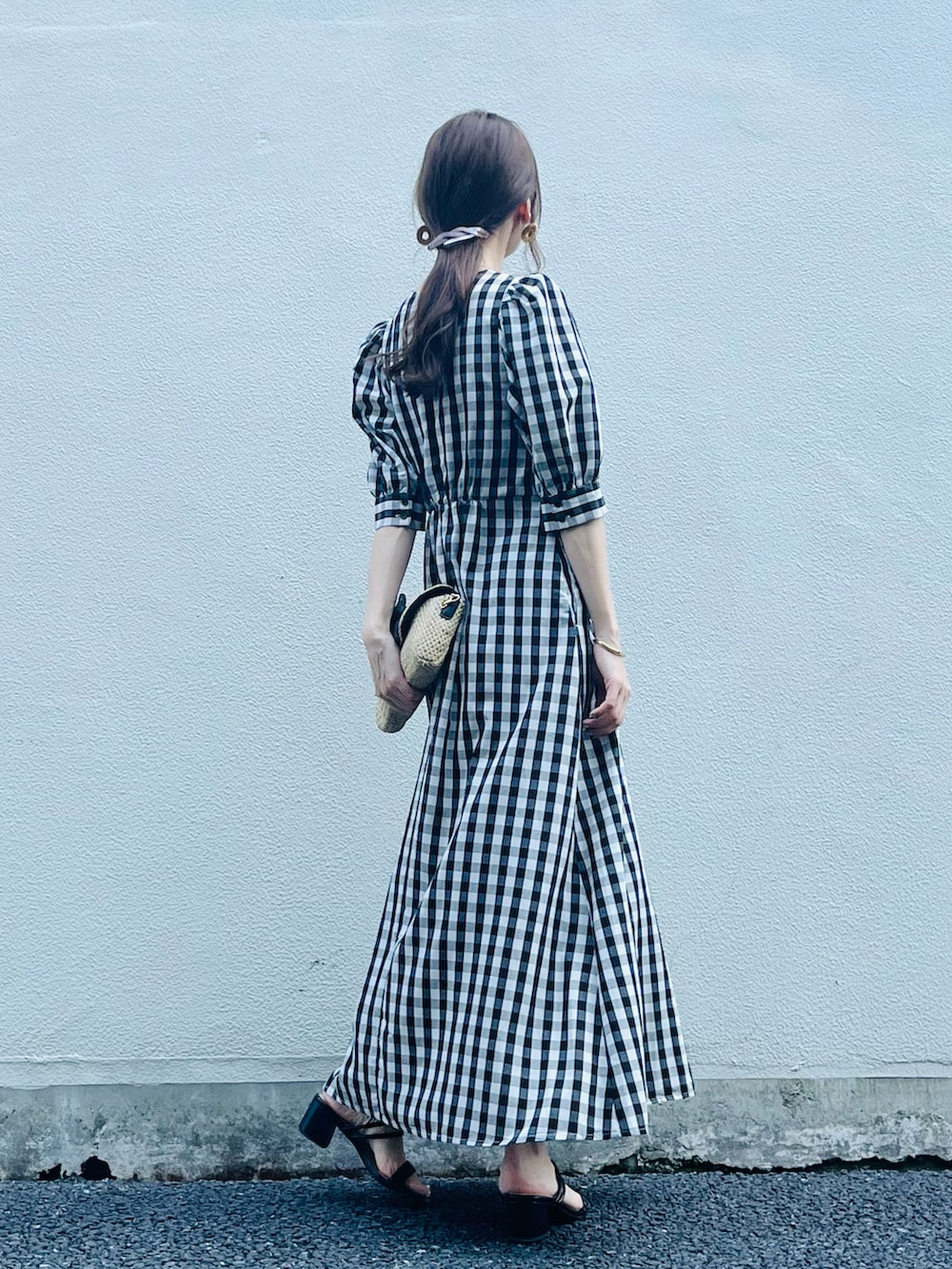 ブラック系のワンピース/ドレス、ベージュ系のバッグ、ブラック系のサンダルを着用したレディースの春コーディネートの3枚目の写真