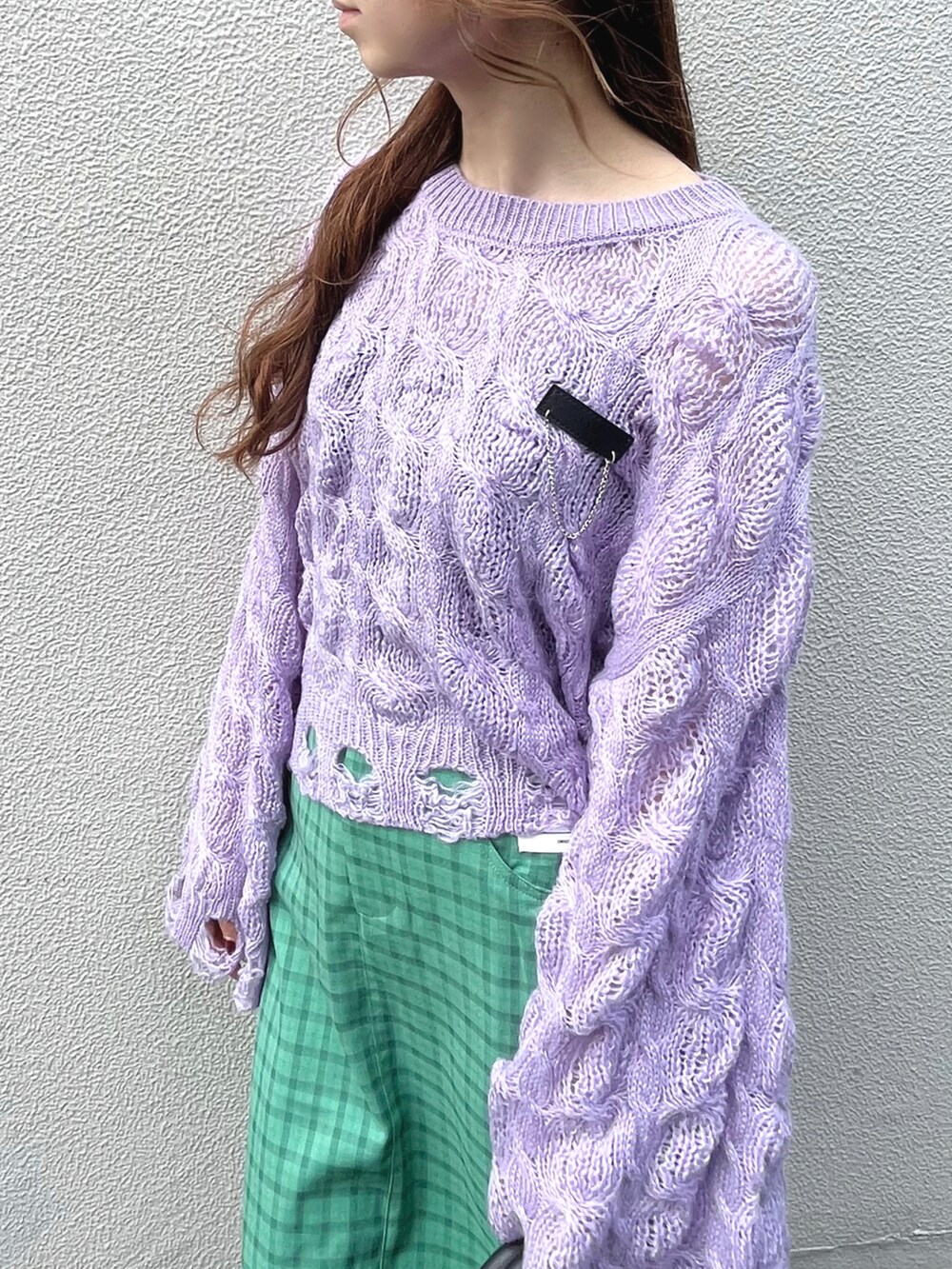 パープル系のニット/セーター、グリーン系のスカート、ブラック系のハンドバッグを着用したレディースの秋コーディネートの5枚目の写真