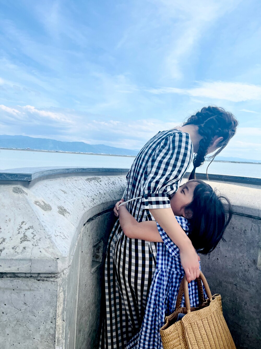 ブラック系のワンピース、ブラック系のサンダル、グレー系のスマホグッズを着用したレディースの夏コーディネートの3枚目の写真