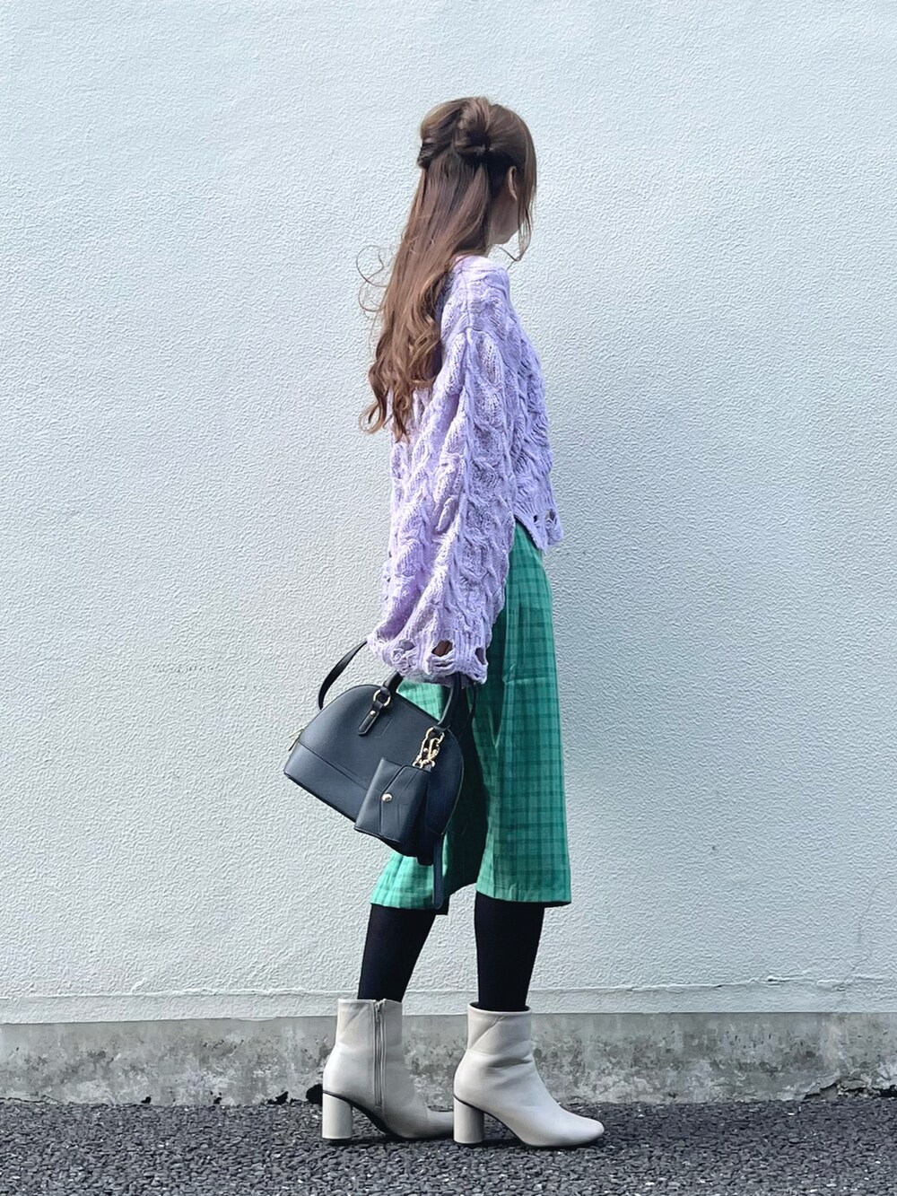パープル系のニット/セーター、グリーン系のスカート、ブラック系のハンドバッグを着用したレディースの秋コーディネートの4枚目の写真