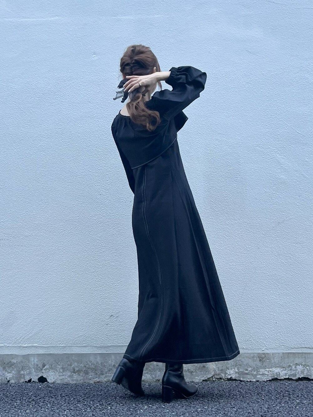 ブラック系のワンピース、ベージュ系のバッグ、ブラック系のブーツを着用したレディースの秋コーディネートの2枚目の写真