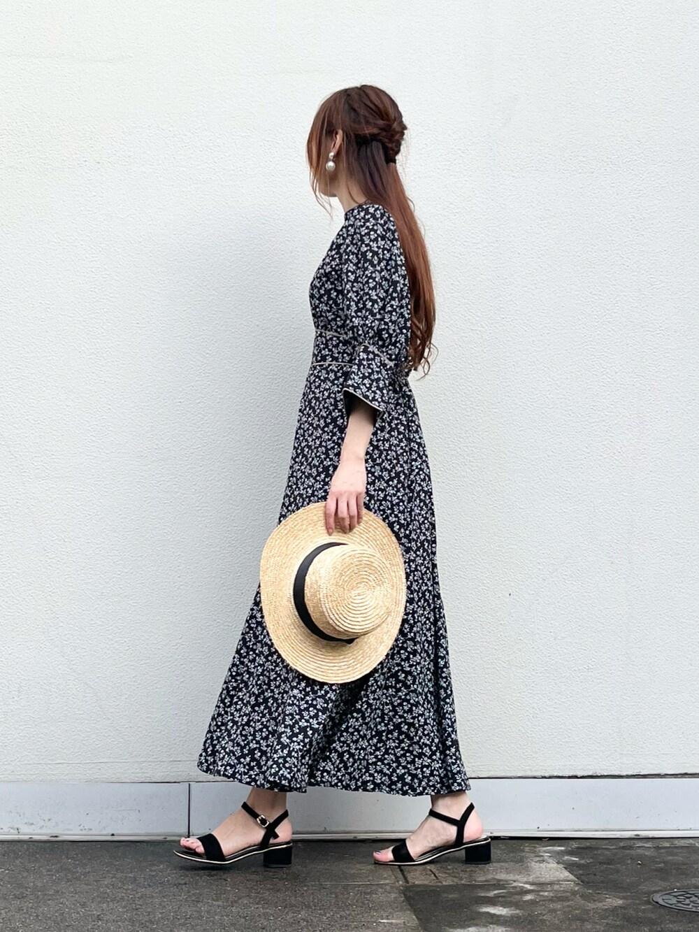 ブラック系のワンピース、ブラック系のサンダル、ベージュ系のハットを着用したレディースの夏コーディネートの2枚目の写真