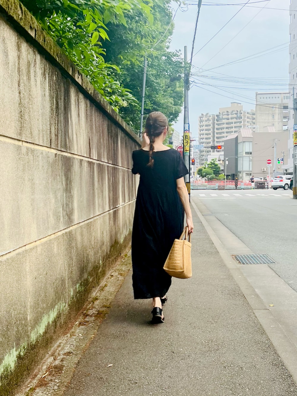 ブラック系のワンピース、ベージュ系のトートバッグ、グレー系のスマホグッズを着用したレディースの夏コーディネートの2枚目の写真