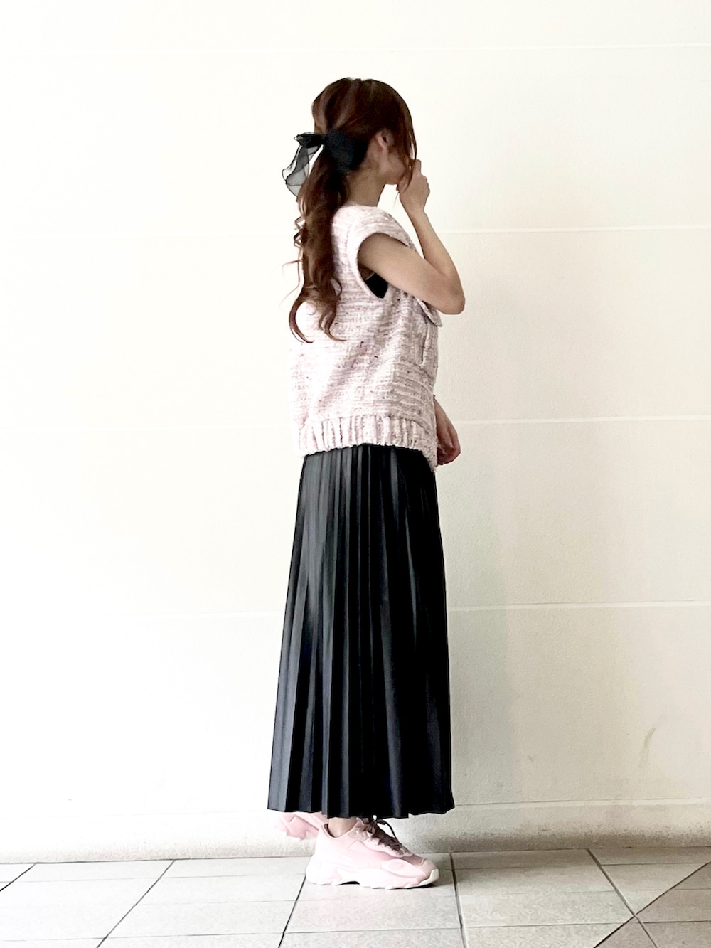 ピンク系のベスト、ブラック系のスカート、ピンク系のスニーカーを着用したレディースの春コーディネートの2枚目の写真