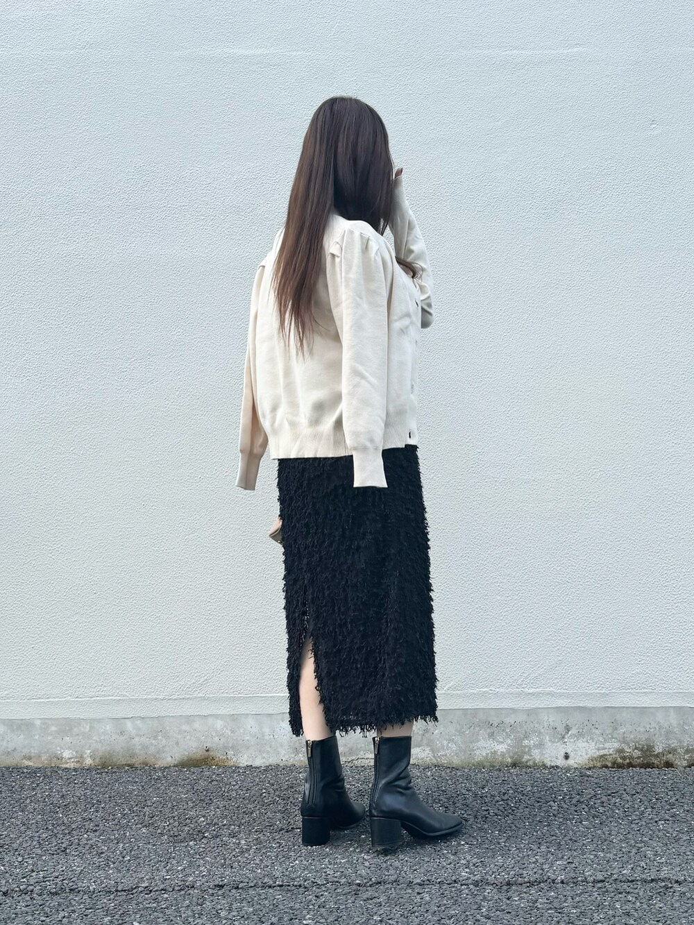 ブラック系のスカート、ブラック系のブーツ、グレー系のスマホグッズを着用したレディースの秋コーディネートの3枚目の写真