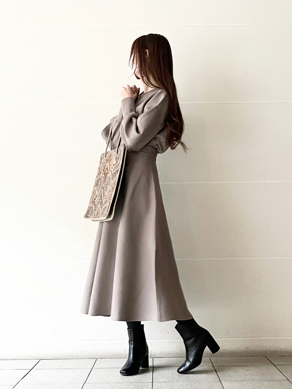 ブルー系のトートバッグ、ブラウン系のニット/セーター、ブラウン系のスカートを着用したレディースの冬コーディネートの2枚目の写真