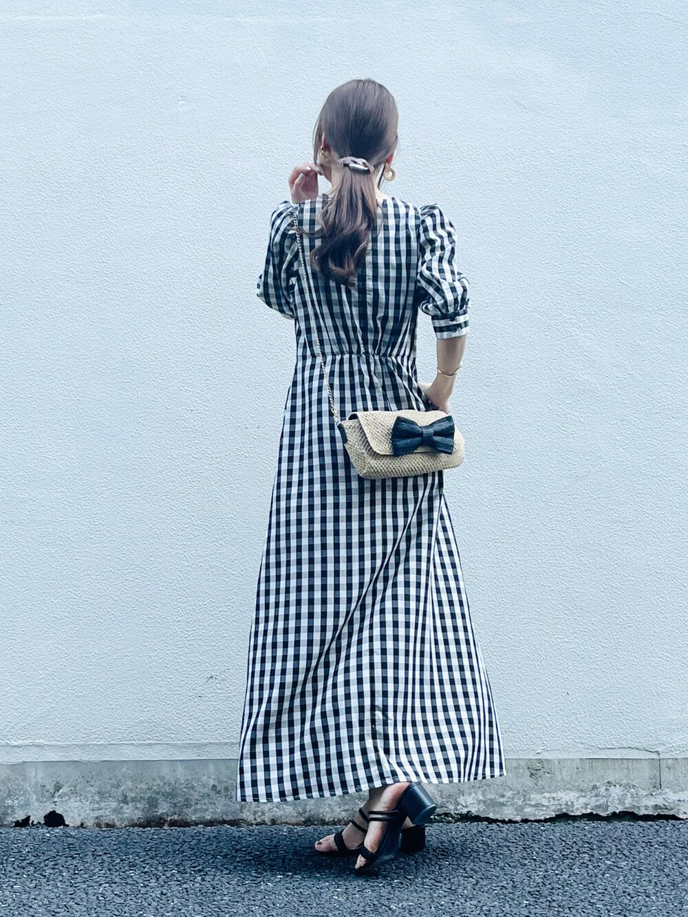 ブラック系のワンピース/ドレス、ベージュ系のバッグ、ブラック系のサンダルを着用したレディースの春コーディネートの5枚目の写真