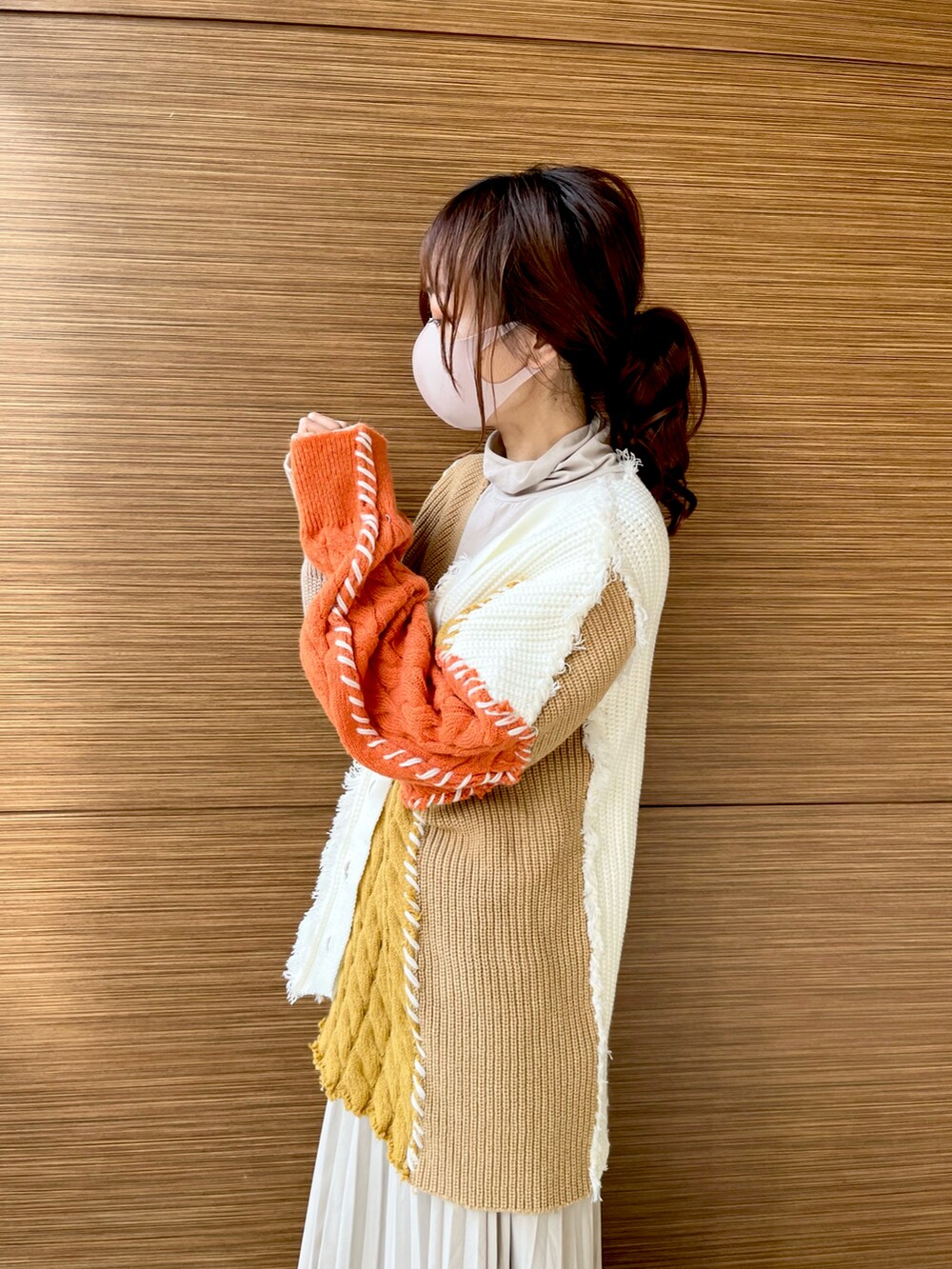 オレンジ系のカーディガン/ボレロ、ベージュ系のTシャツ/カットソー、ベージュ系のスカートを着用したレディースの冬コーディネートの2枚目の写真