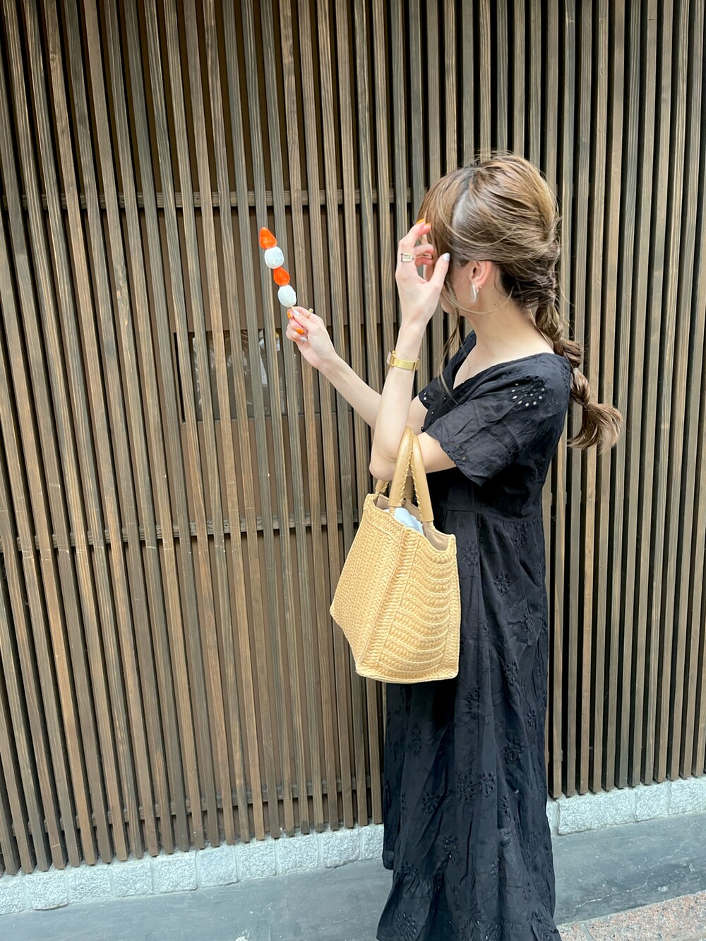 ブラック系のワンピース、ベージュ系のトートバッグ、グレー系のスマホグッズを着用したレディースの夏コーディネートの4枚目の写真