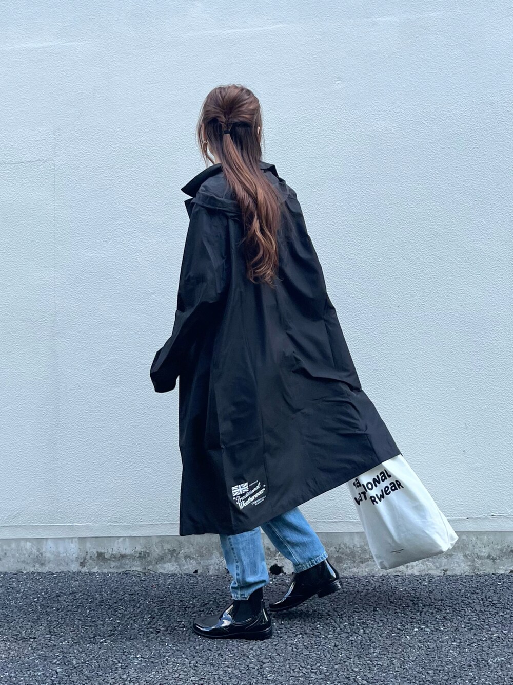 ブラック系のレインシューズ、ホワイト系のトートバッグ、ブルー系のデニムパンツを着用したレディースの夏コーディネートの2枚目の写真