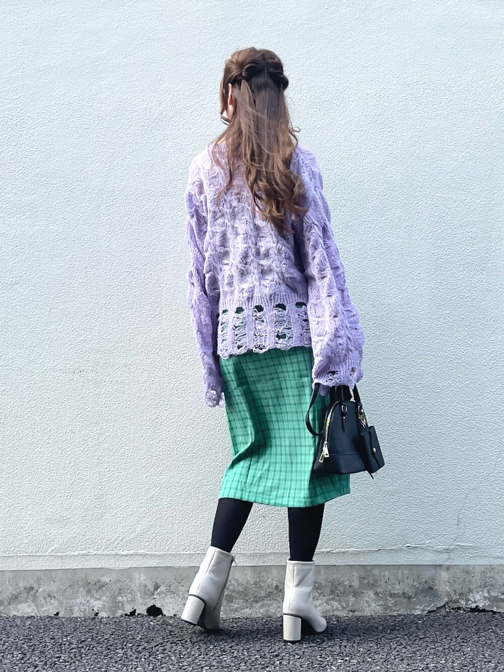 パープル系のニット/セーター、グリーン系のスカート、ブラック系のハンドバッグを着用したレディースの秋コーディネートの3枚目の写真