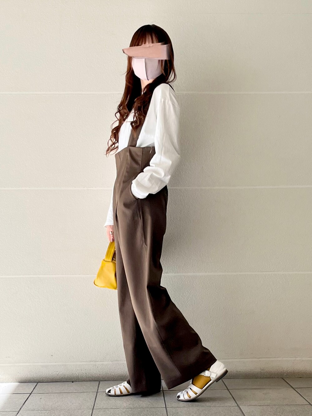 ブラウン系のサロペット/オーバーオール、イエロー系のハンドバッグ、ホワイト系のTシャツ/カットソーを着用したレディースの冬コーディネートの2枚目の写真