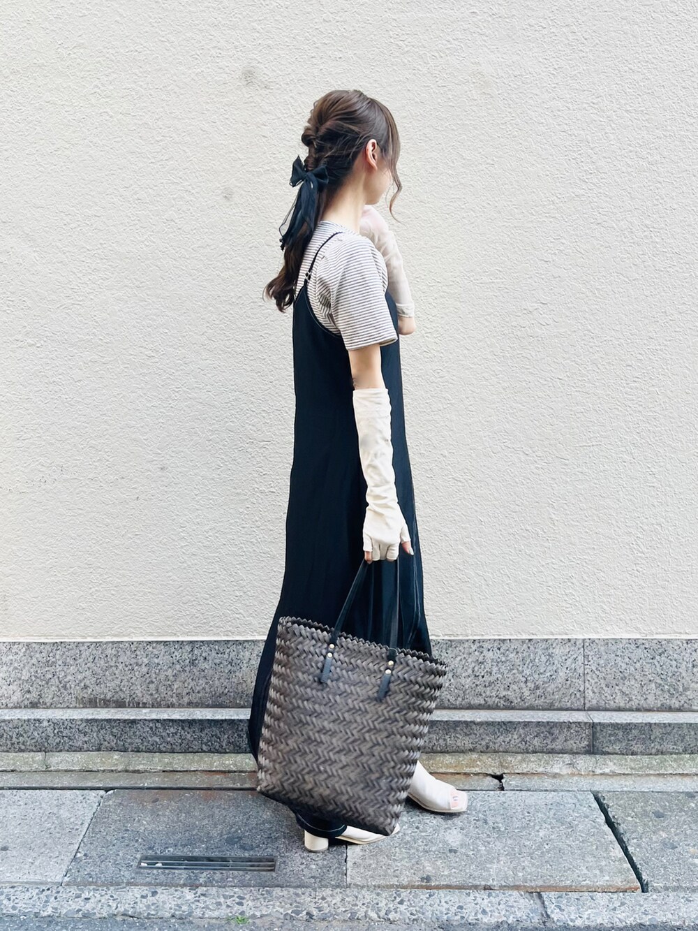 ブラウン系のバッグ、ブラック系のワンピース、ホワイト系のニット/セーターを着用したレディースの春コーディネートの2枚目の写真