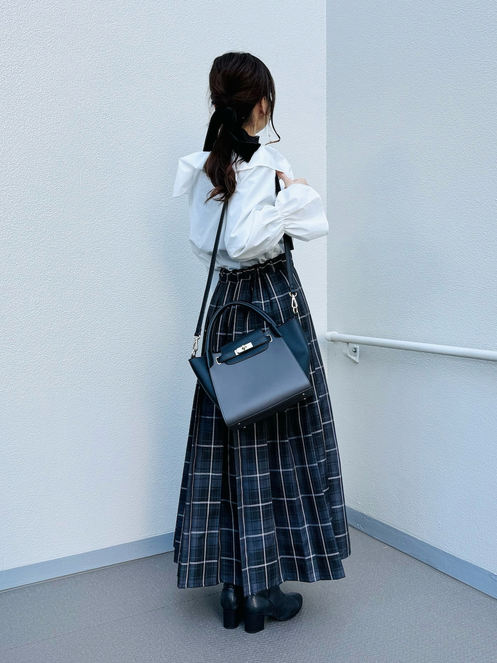 ブラック系のブーツ、ブラック系のスカート、ホワイト系のシャツ/ブラウスを着用したレディースの冬コーディネートの2枚目の写真