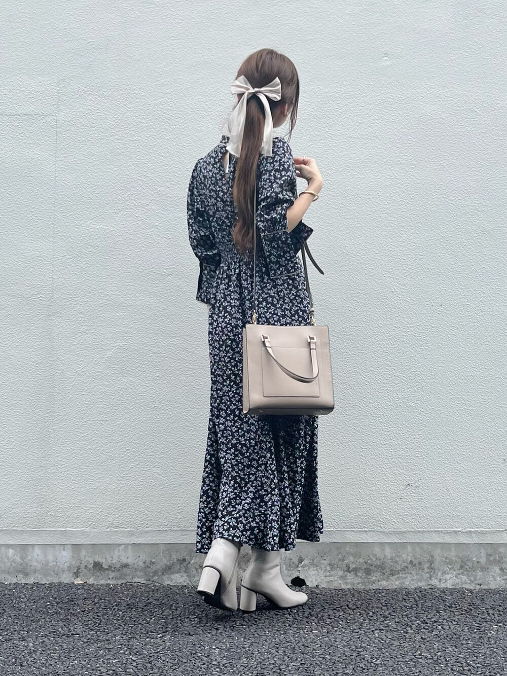 ベージュ系のバッグ、ブラック系のワンピース、ホワイト系のブーツを着用したレディースの秋コーディネートの5枚目の写真