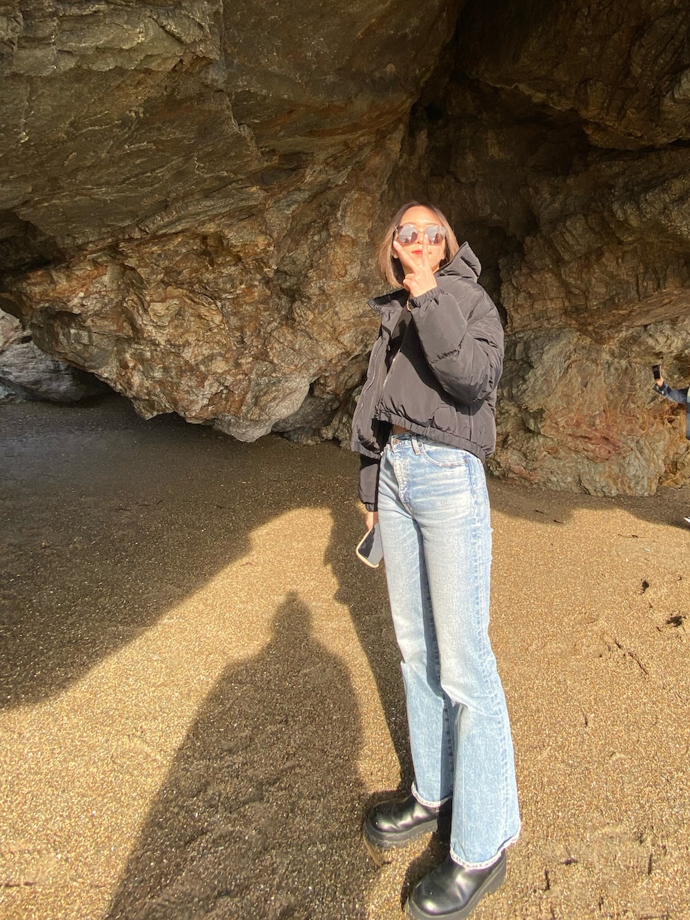 ブルー系のデニムパンツ、ブラック系のブーツ、ブラック系のダウンジャケット/コートを着用したレディースの冬コーディネートの2枚目の写真