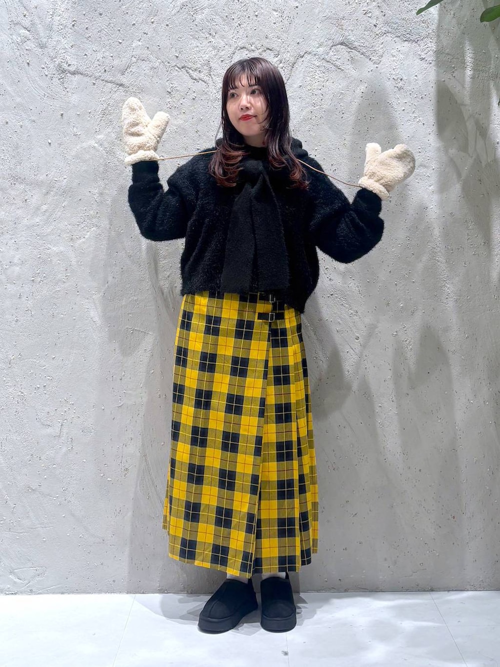 イエロー系のスカート、ブラック系のその他シューズ、ブラック系のニット/セーターを着用したレディースの冬コーディネートの2枚目の写真