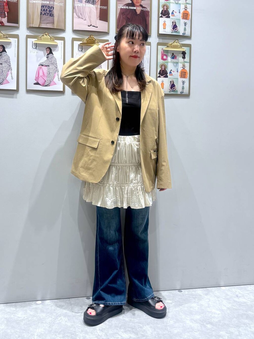 ブラック系のサンダル、ベージュ系のテーラードジャケット、ブルー系のデニムパンツを着用したレディースの秋コーディネートの2枚目の写真