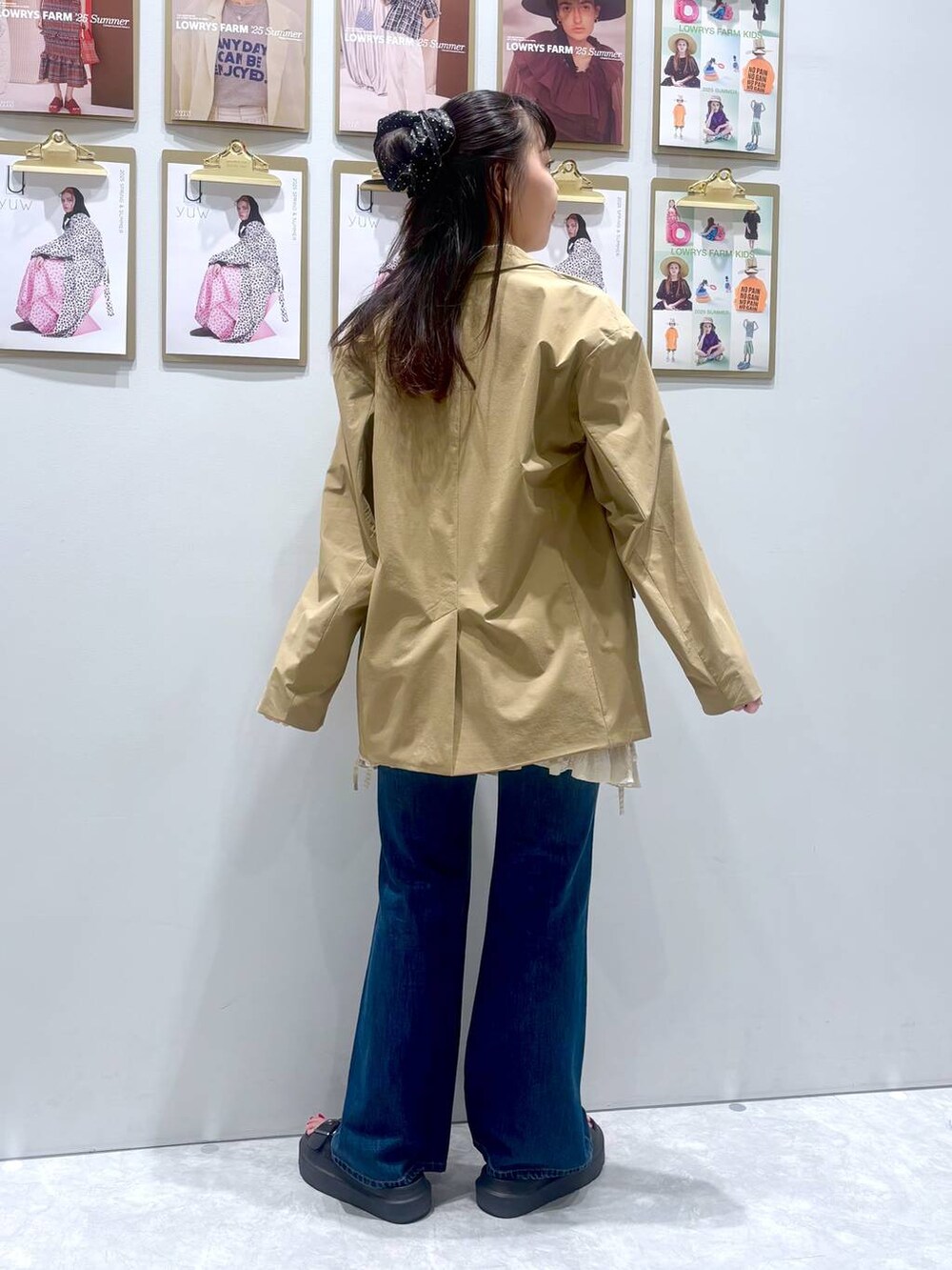 ブラック系のサンダル、ベージュ系のテーラードジャケット、ブルー系のデニムパンツを着用したレディースの秋コーディネートの5枚目の写真