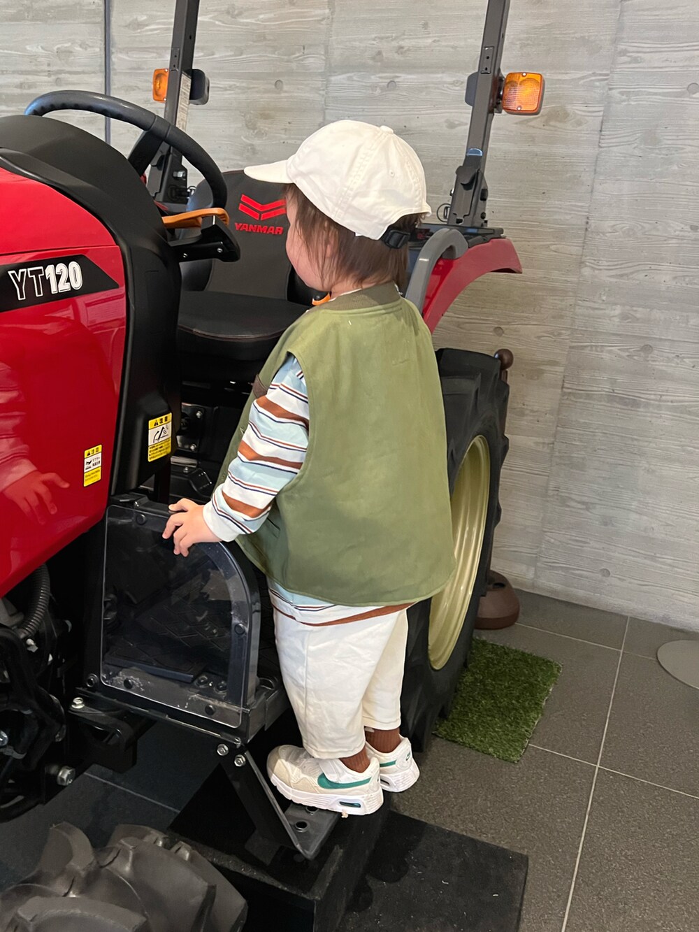 グリーン系のベスト、ベージュ系のTシャツ/カットソー、ホワイト系のパンツを着用したキッズの春コーディネートの3枚目の写真