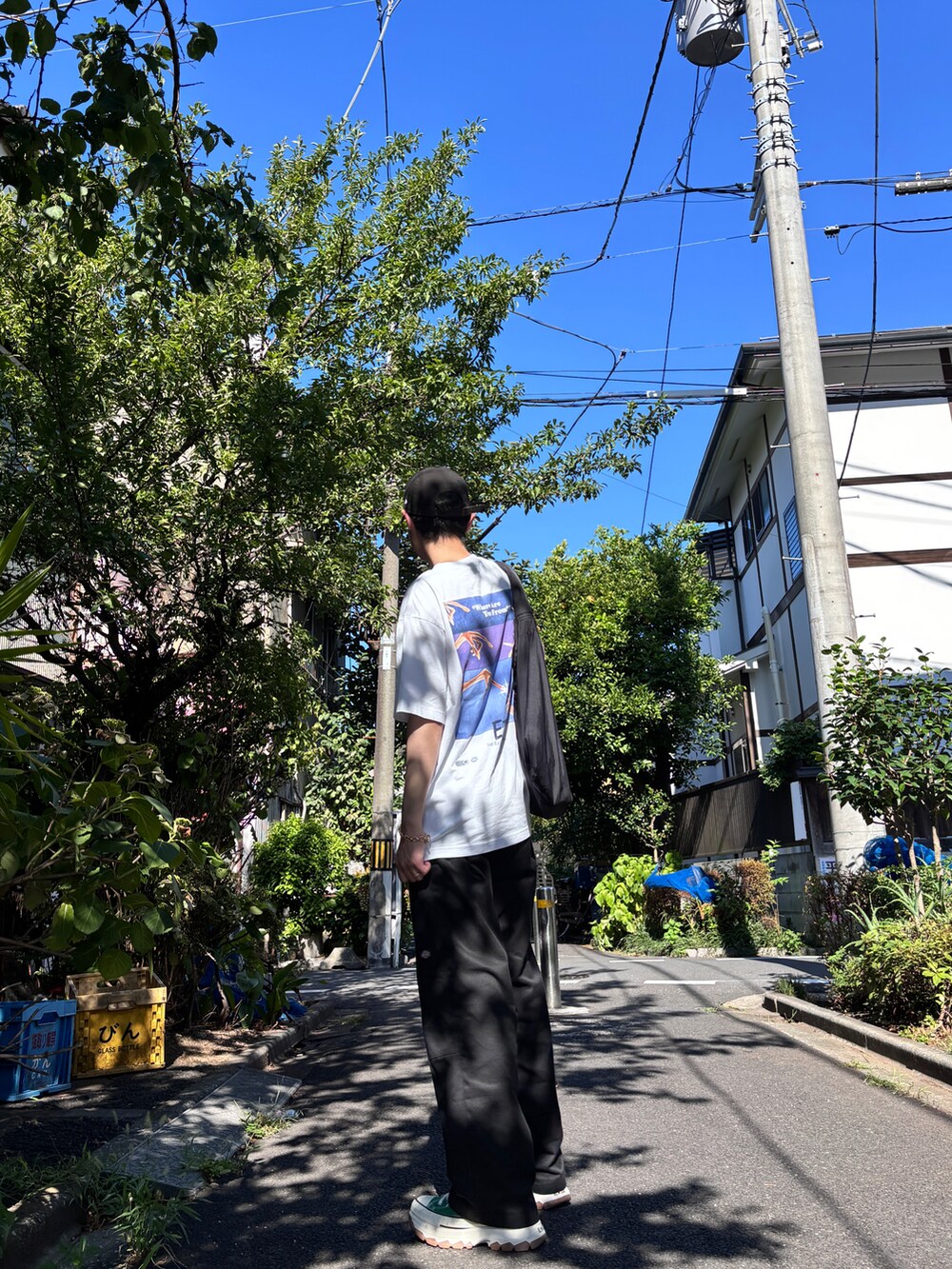 ブラック系のチノパンツ、グリーン系のスニーカー、ホワイト系のTシャツ/カットソーを着用したメンズの夏コーディネートの2枚目の写真
