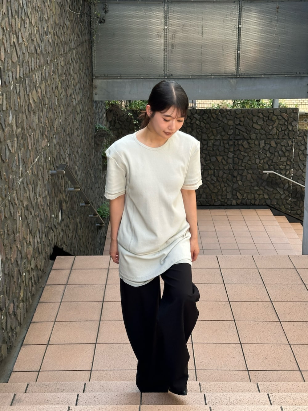 ブラック系のスラックス、ベージュ系のTシャツ/カットソーを着用したレディースの夏コーディネートの2枚目の写真