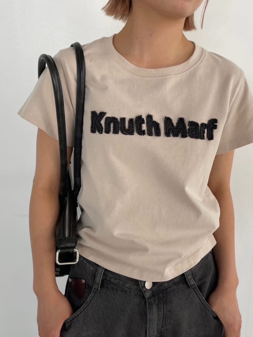 ベージュ系のTシャツ/カットソー、グレー系のデニムパンツを着用したレディースの夏コーディネートの2枚目の写真
