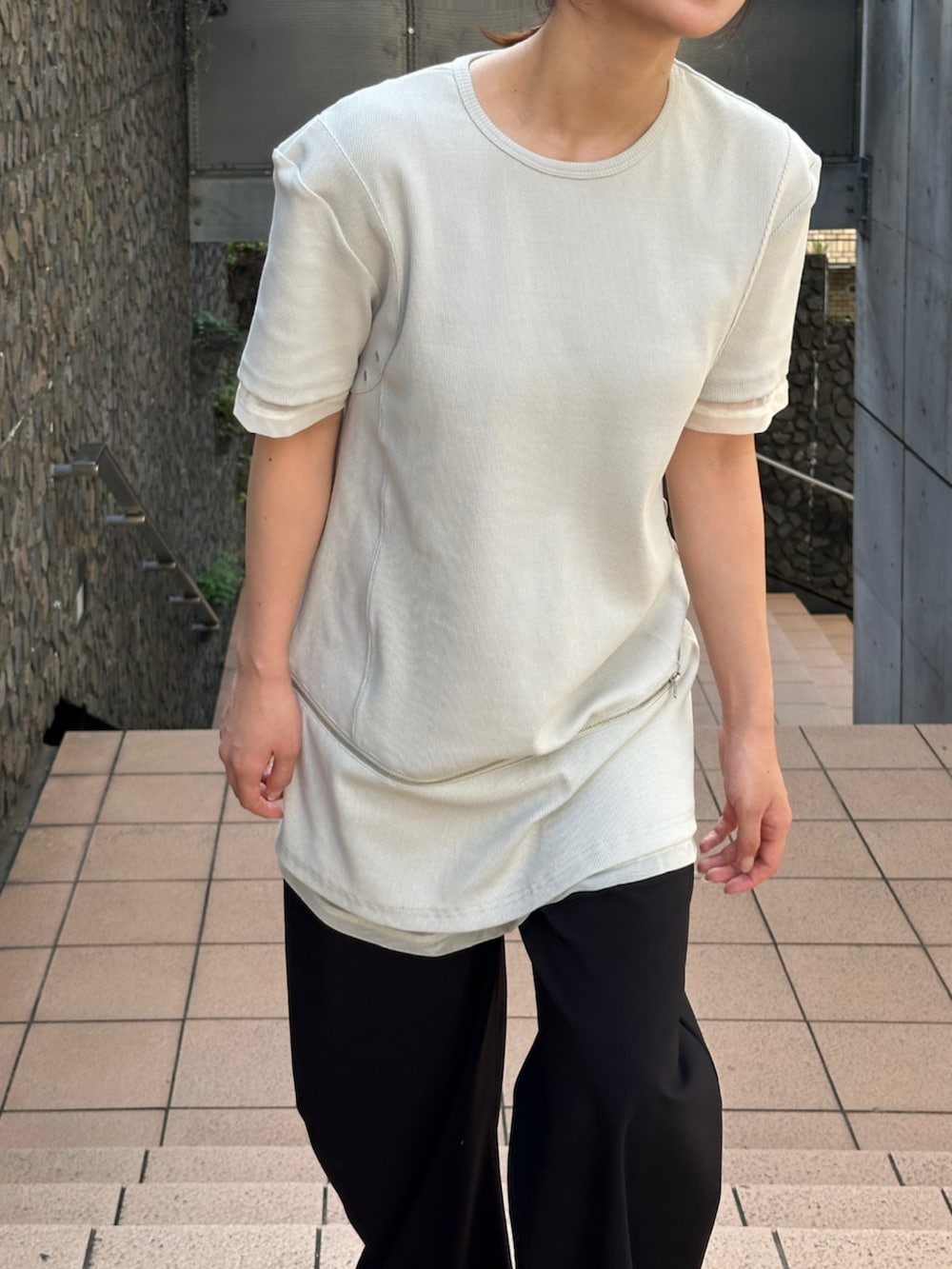 ブラック系のスラックス、ベージュ系のTシャツ/カットソーを着用したレディースの夏コーディネートの3枚目の写真