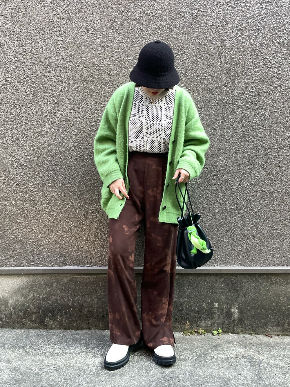 ブラック系のハンドバッグ、グリーン系のカーディガン/ボレロ、ブラウン系のその他パンツを着用したレディースの春コーディネートの2枚目の写真