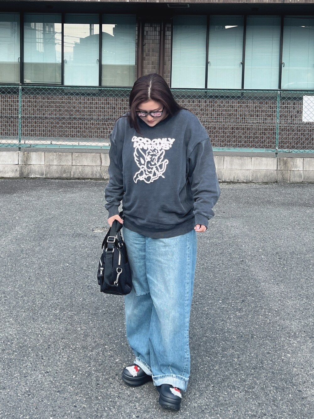 ブラック系のスウェット、ブルー系のデニムパンツ、ブラック系のハンドバッグを着用したレディースの秋コーディネートの2枚目の写真