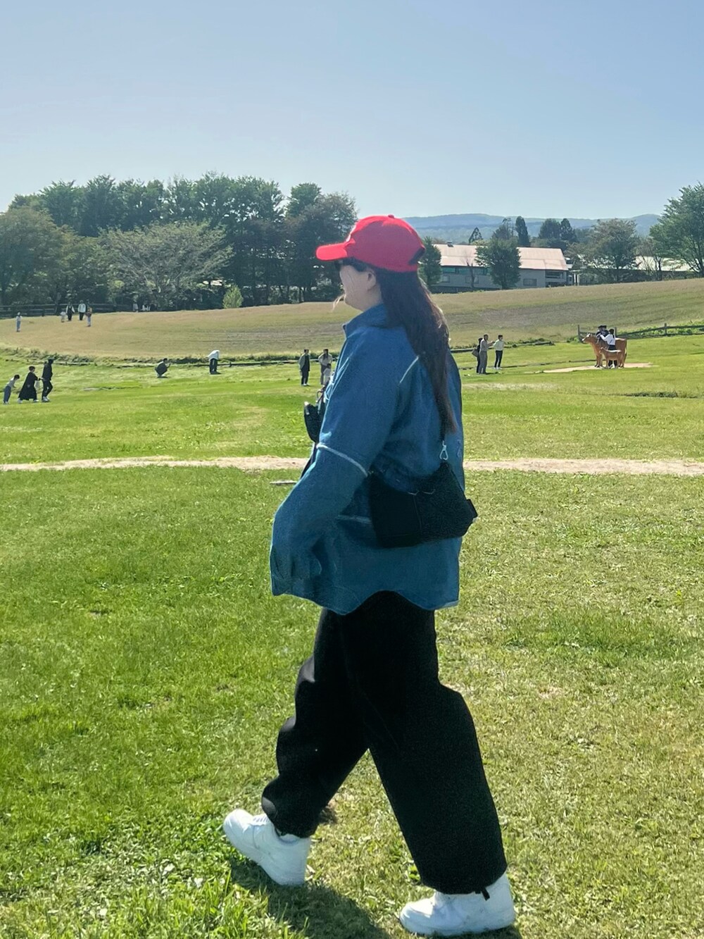 ブラック系のショルダーバッグ、ブラック系のスウェットパンツ、ホワイト系のスニーカーを着用したレディースの秋コーディネートの2枚目の写真