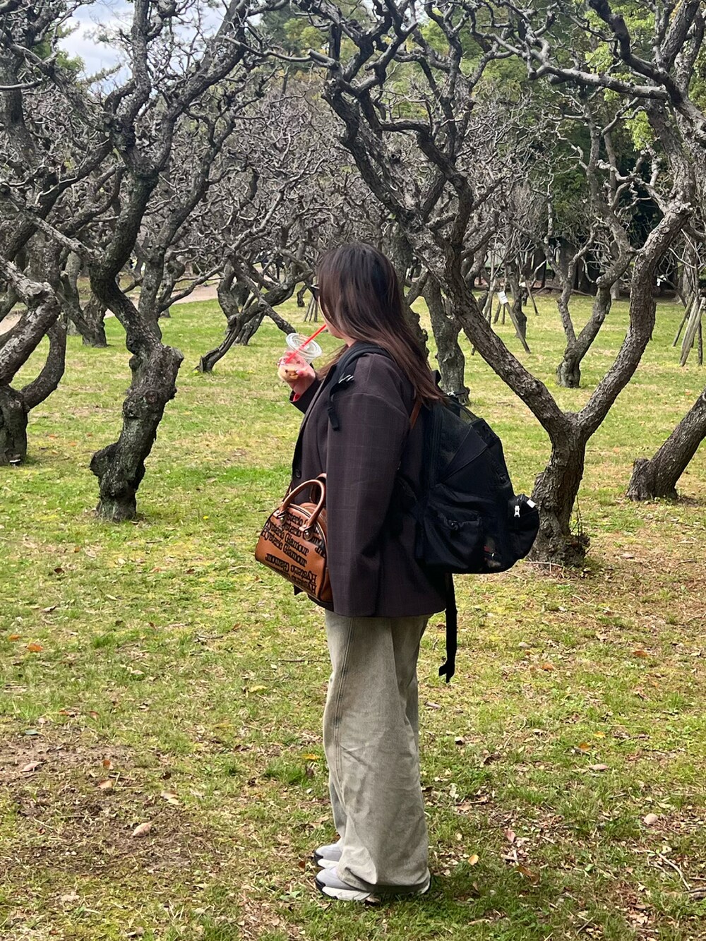 ブラウン系のテーラードジャケット、レッド系のTシャツ/カットソー、ブルー系のデニムパンツを着用したレディースの春コーディネートの2枚目の写真