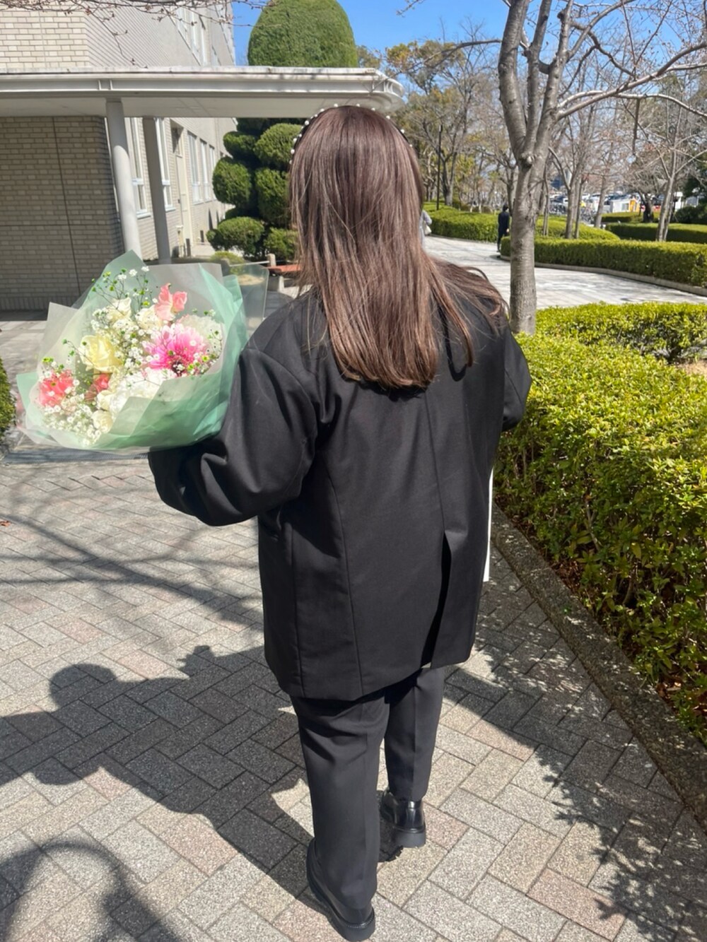 ブラック系のテーラードジャケット、ブラック系のバッグ、ブラック系のローファーを着用したレディースの春コーディネートの3枚目の写真