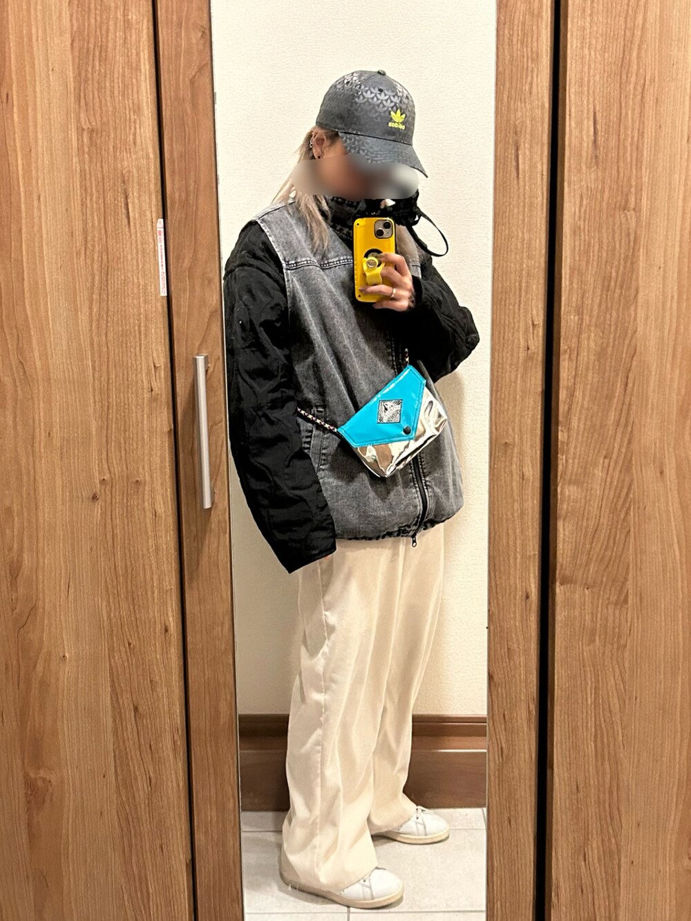 シルバー系のショルダーバッグ、ブラック系のベスト、ブラック系のブルゾンを着用したレディースの春コーディネートの2枚目の写真