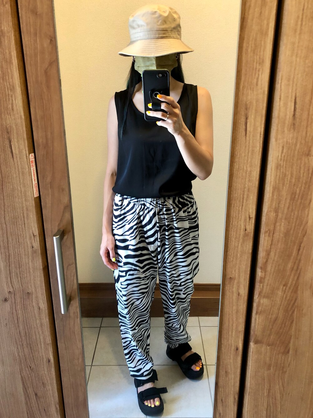 ブラック系のタンクトップ、イエロー系のトートバッグ、ブラック系のサンダルを着用したレディースの夏コーディネートの2枚目の写真