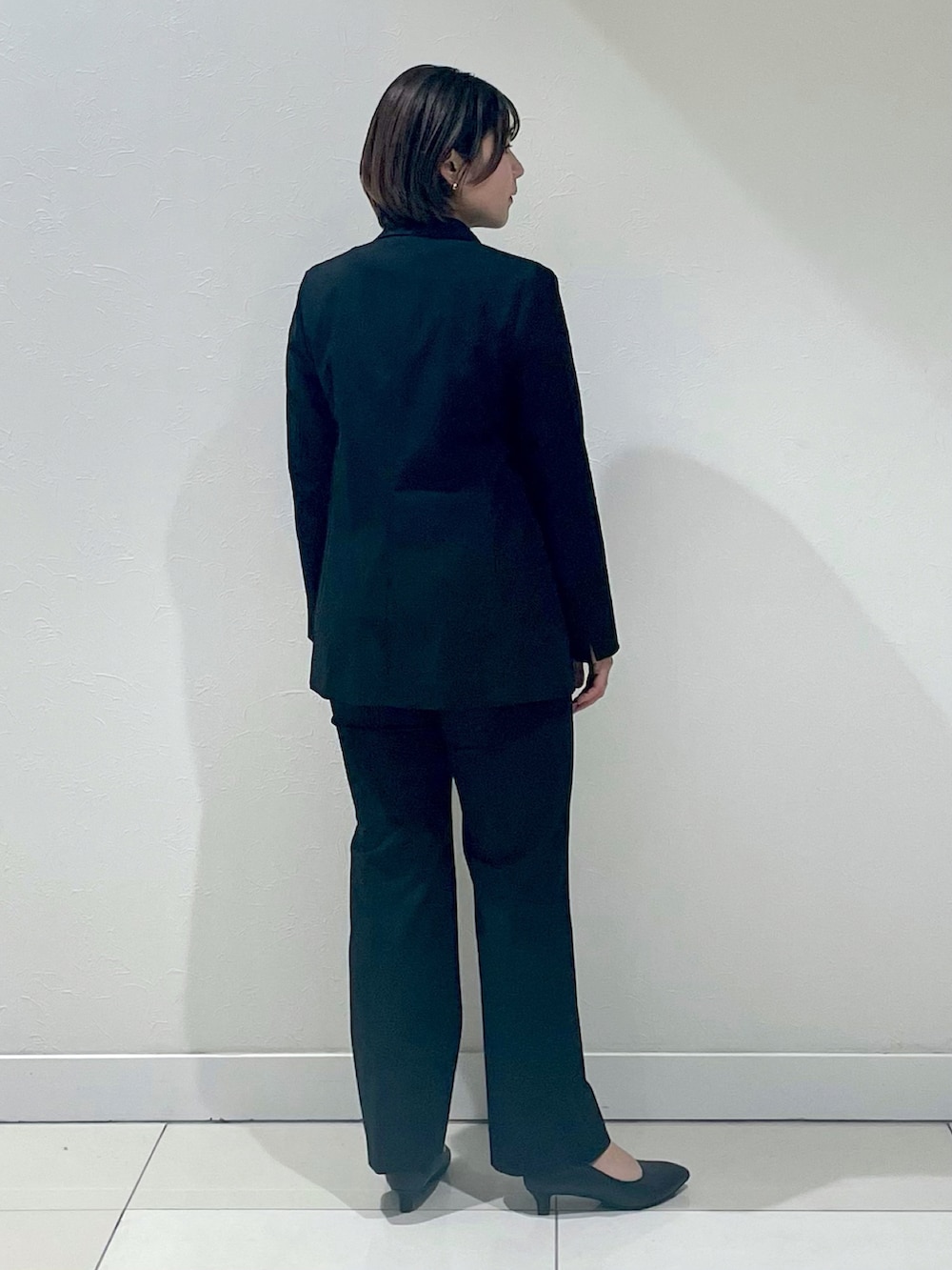 ブラック系のスーツジャケット、グリーン系のTシャツ/カットソー、ブラック系のスーツパンツを着用したレディースの春コーディネートの2枚目の写真