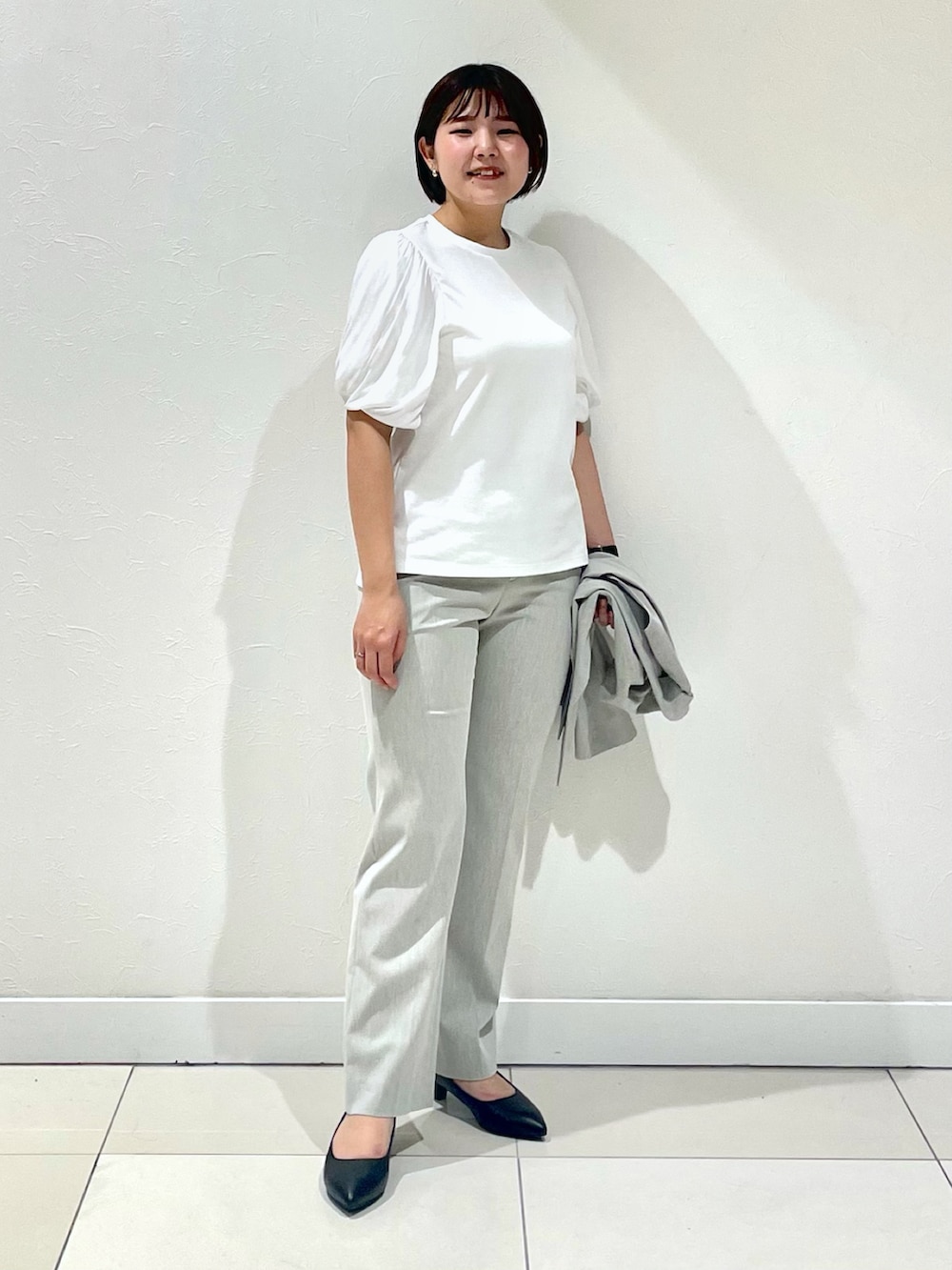 グレー系のベスト、ホワイト系のTシャツ/カットソー、グレー系のスーツパンツを着用したレディースの春コーディネートの2枚目の写真