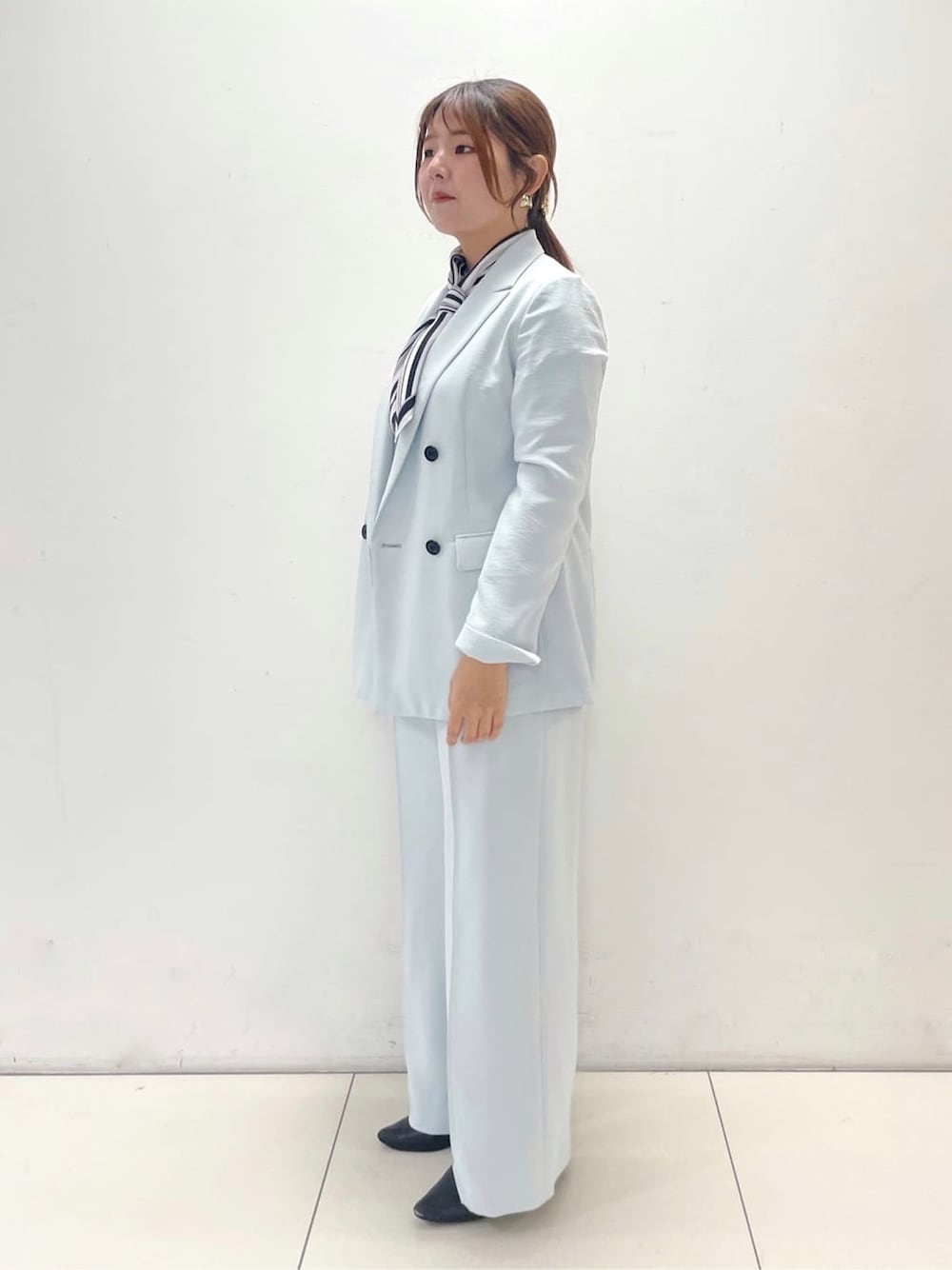グリーン系のスーツジャケット、グリーン系のスーツパンツ、ホワイト系のニット/セーターを着用したレディースの春コーディネートの5枚目の写真