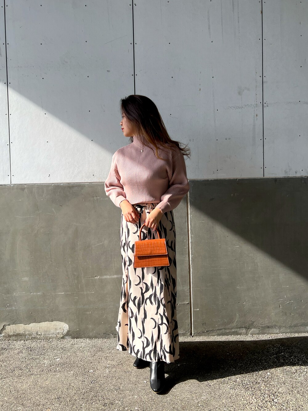 ピンク系のニット/セーター、イエロー系のショルダーバッグ、ベージュ系のスカートを着用したレディースの冬コーディネートの2枚目の写真