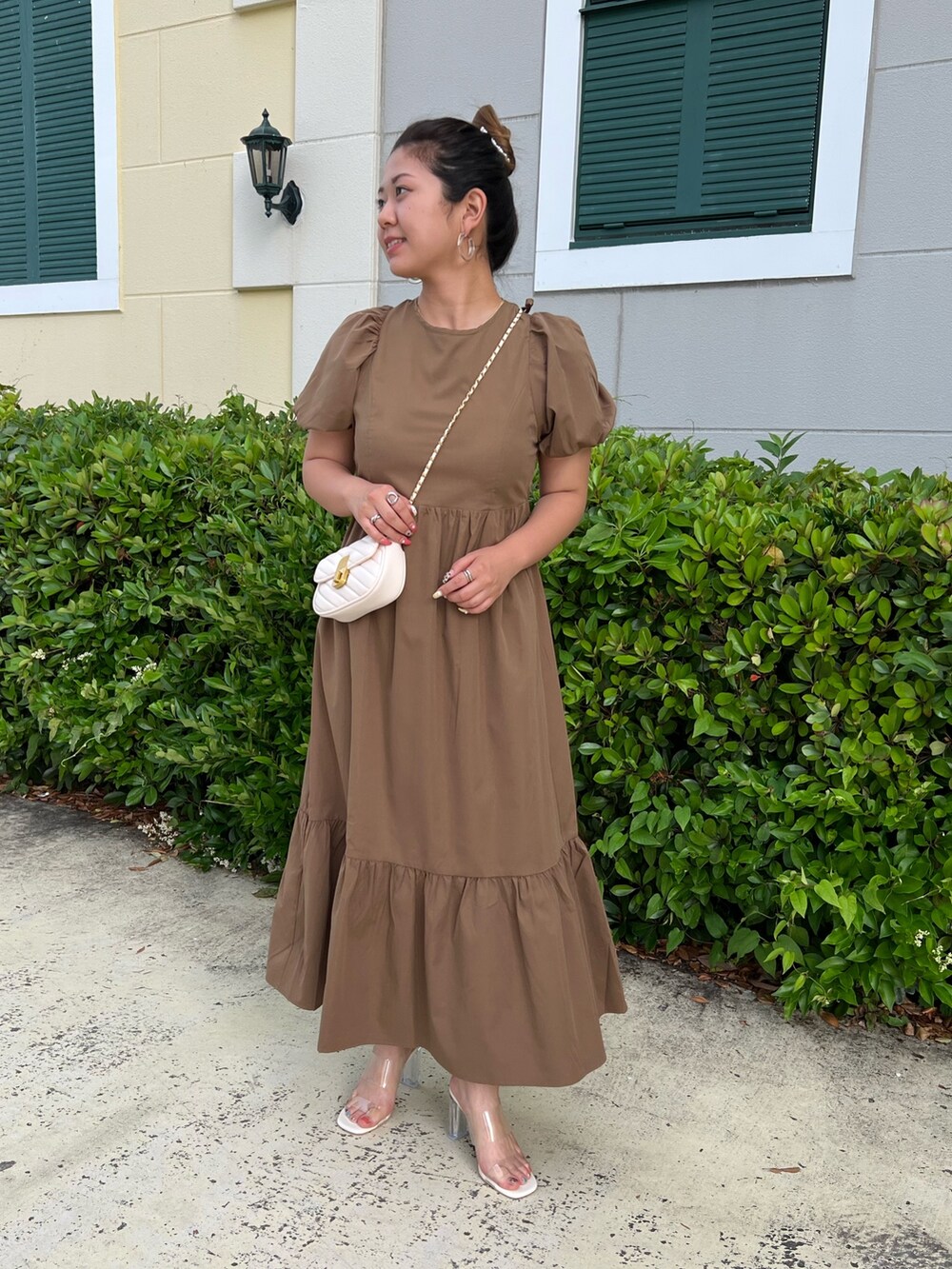 ブラック系のショルダーバッグ、ブラウン系のワンピース、ホワイト系のサンダルを着用したレディースの夏コーディネートの2枚目の写真