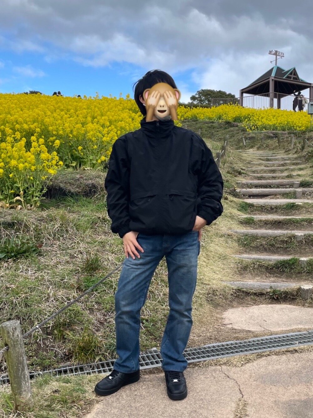 ブラック系のナイロンジャケット、ブルー系のデニムパンツ、ブラック系のスニーカーを着用したメンズの春コーディネートの2枚目の写真