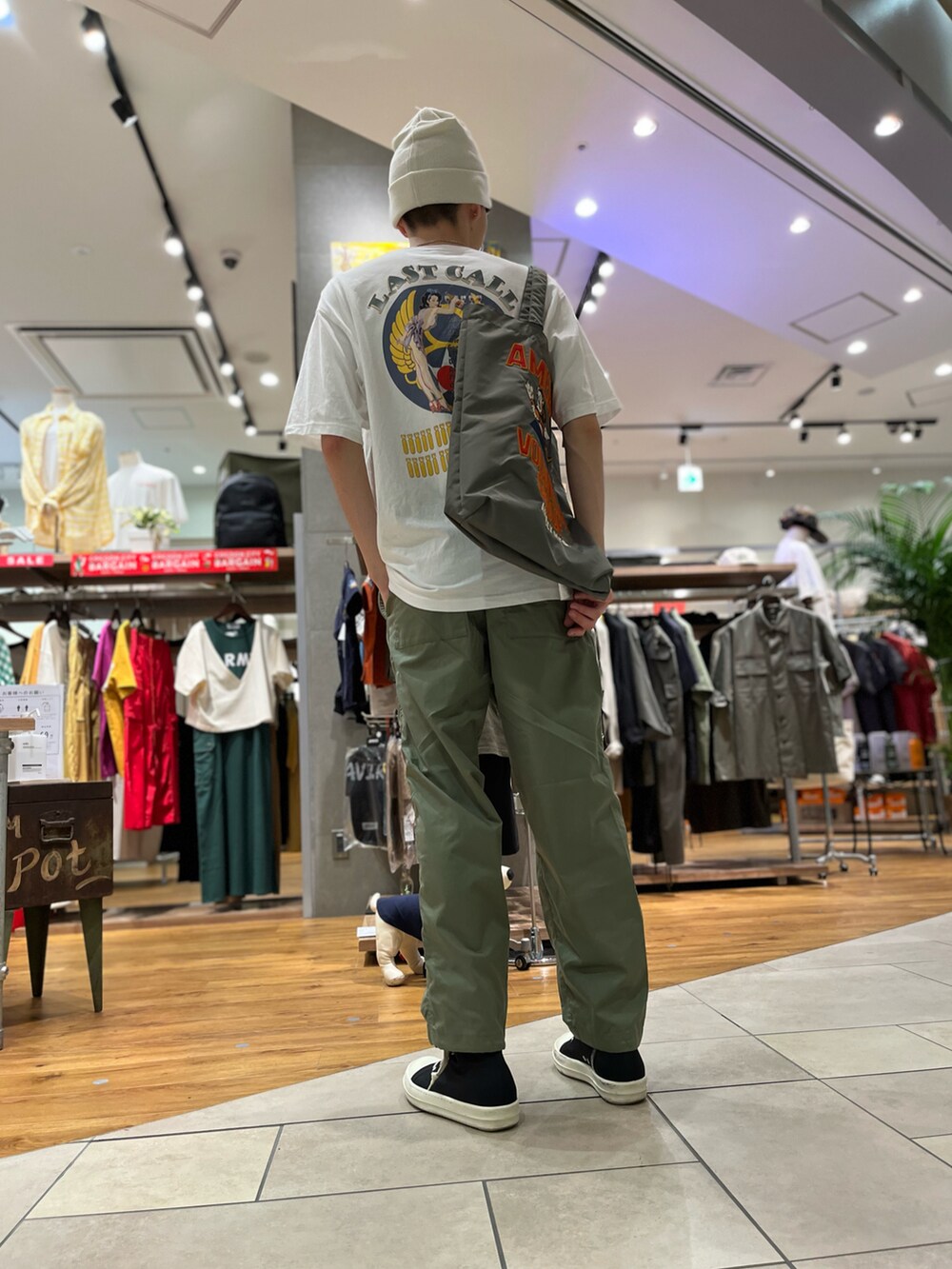 グリーン系のトートバッグ、グリーン系のパンツ、ホワイト系のTシャツ/カットソーを着用したメンズの夏コーディネートの2枚目の写真