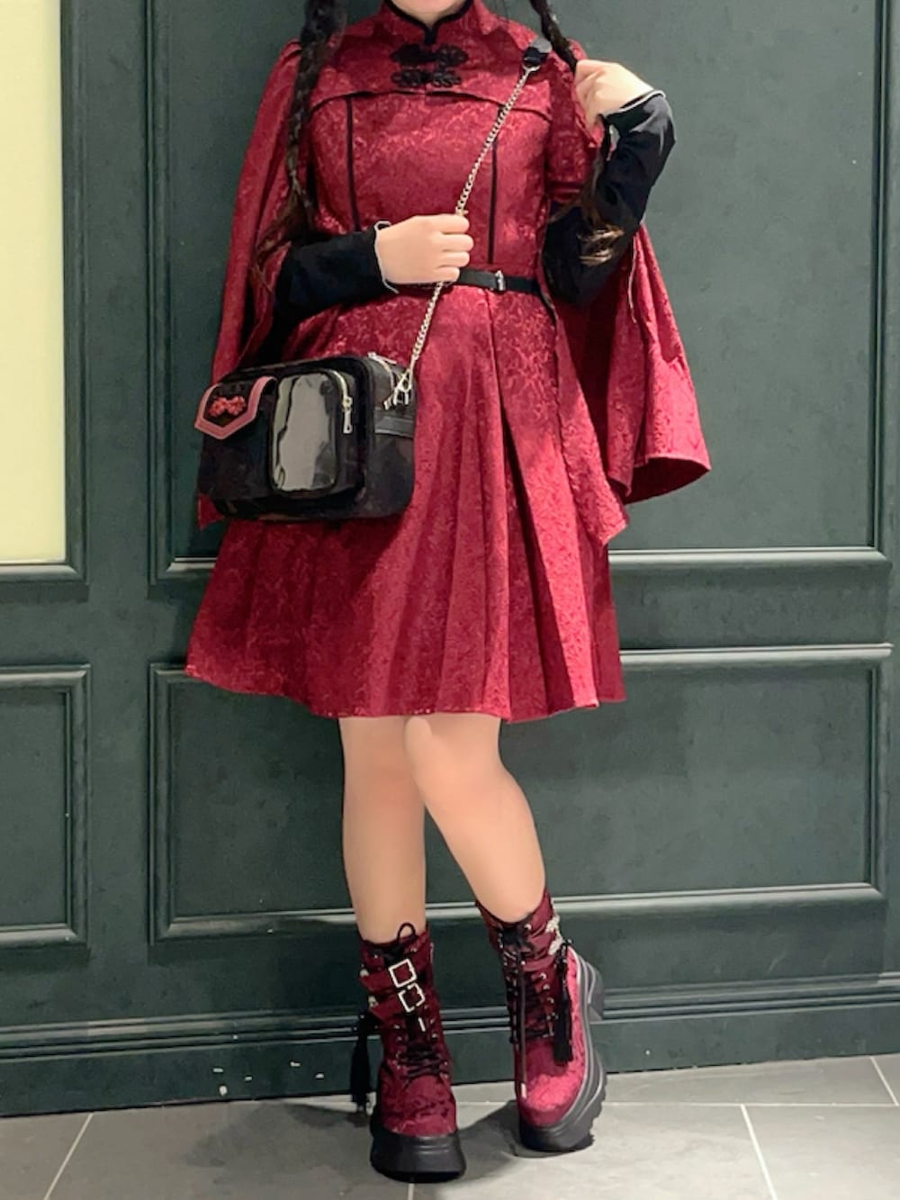 レッド系のブーツ、レッド系のワンピース、レッド系のショルダーバッグを着用したレディースの秋コーディネートの2枚目の写真