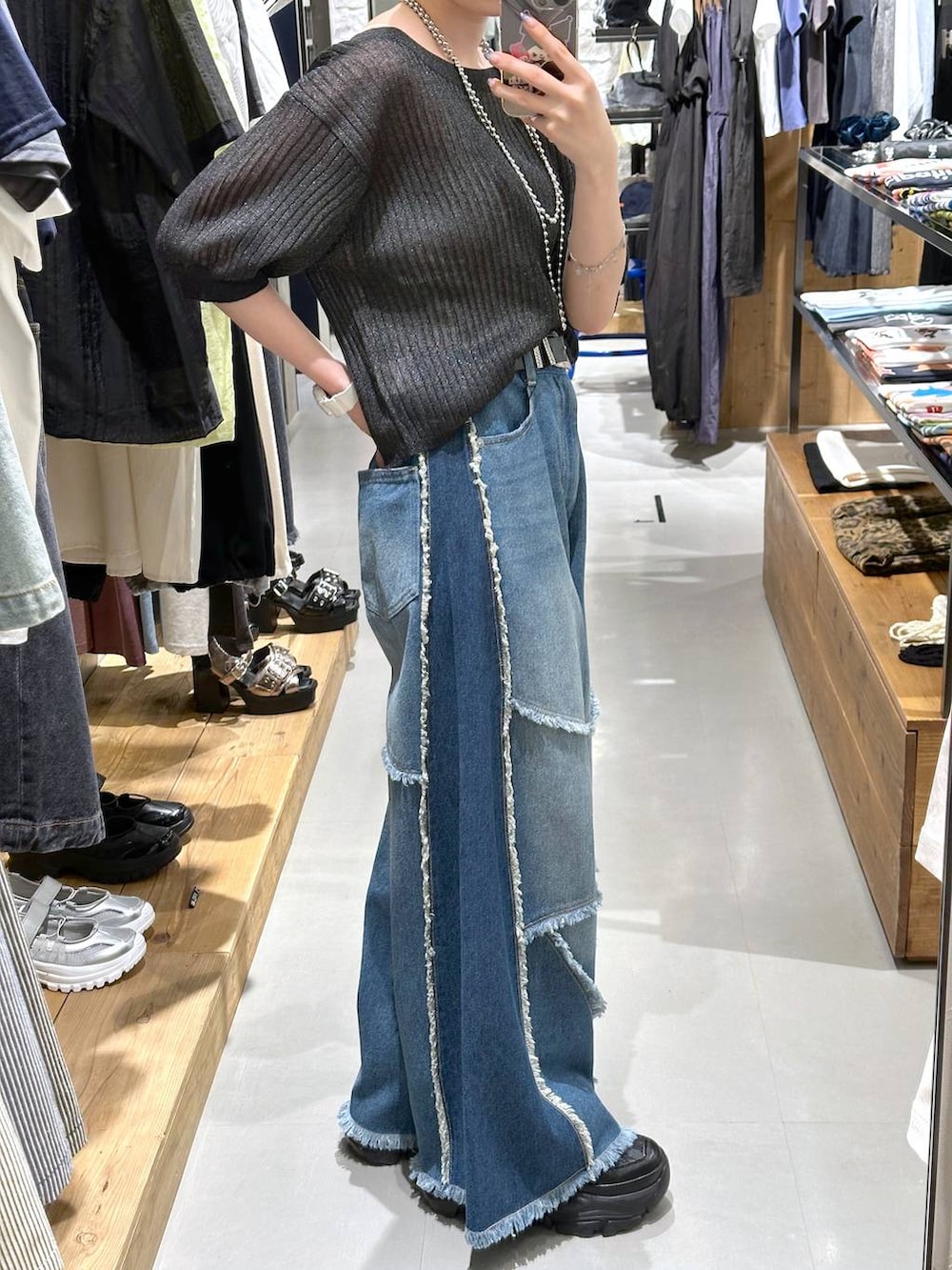 ブルー系のデニムパンツ、ブラック系のニット/セーター、ブラック系のベルトを着用したレディースの夏コーディネートの2枚目の写真