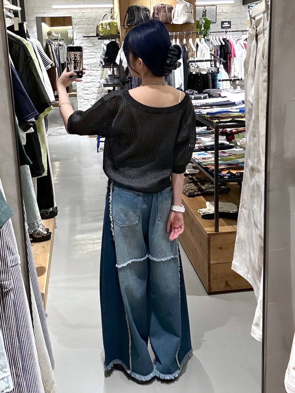ブルー系のデニムパンツ、ブラック系のニット/セーター、ブラック系のベルトを着用したレディースの夏コーディネートの3枚目の写真