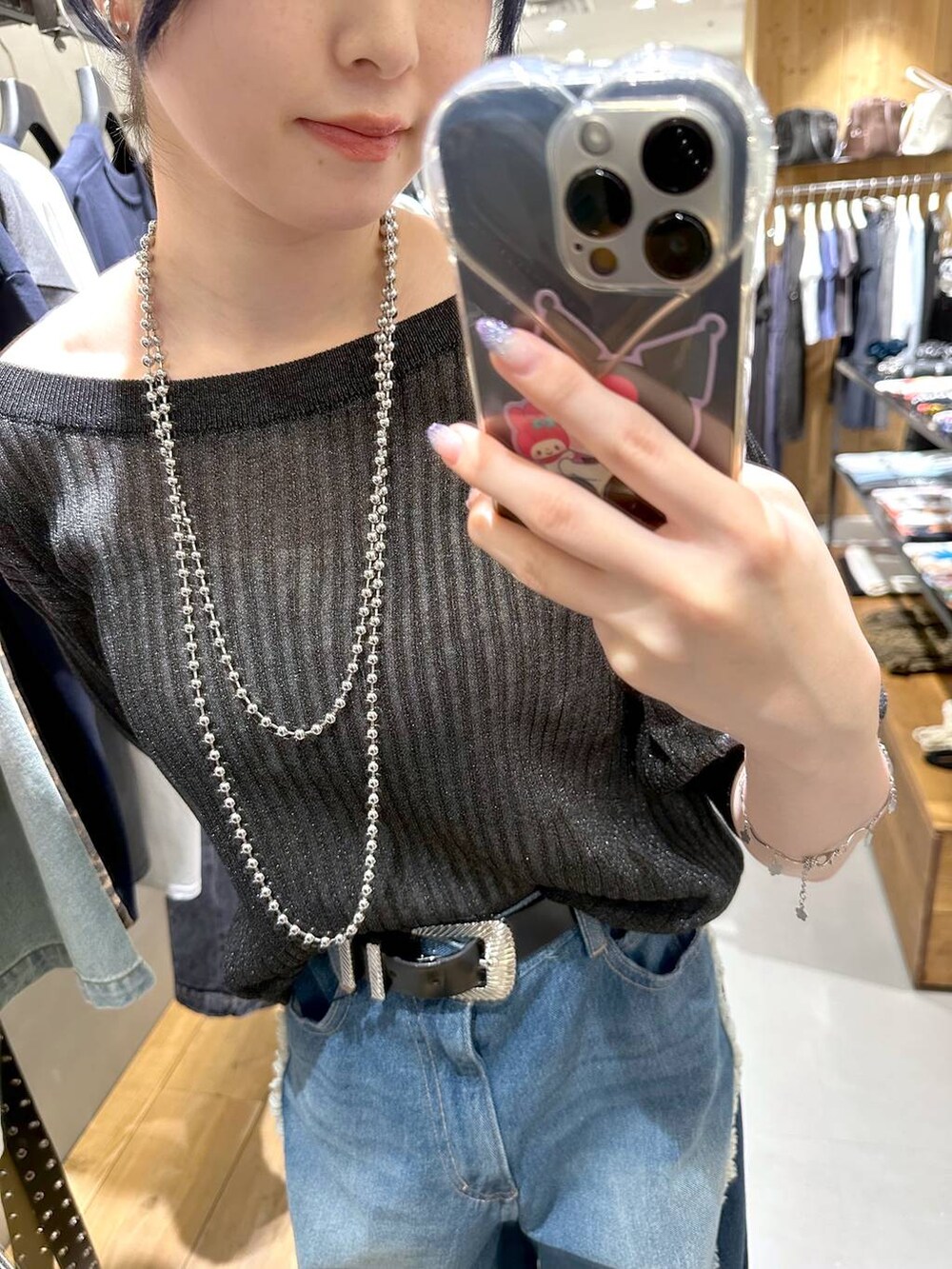 ブルー系のデニムパンツ、ブラック系のニット/セーター、ブラック系のベルトを着用したレディースの夏コーディネートの4枚目の写真