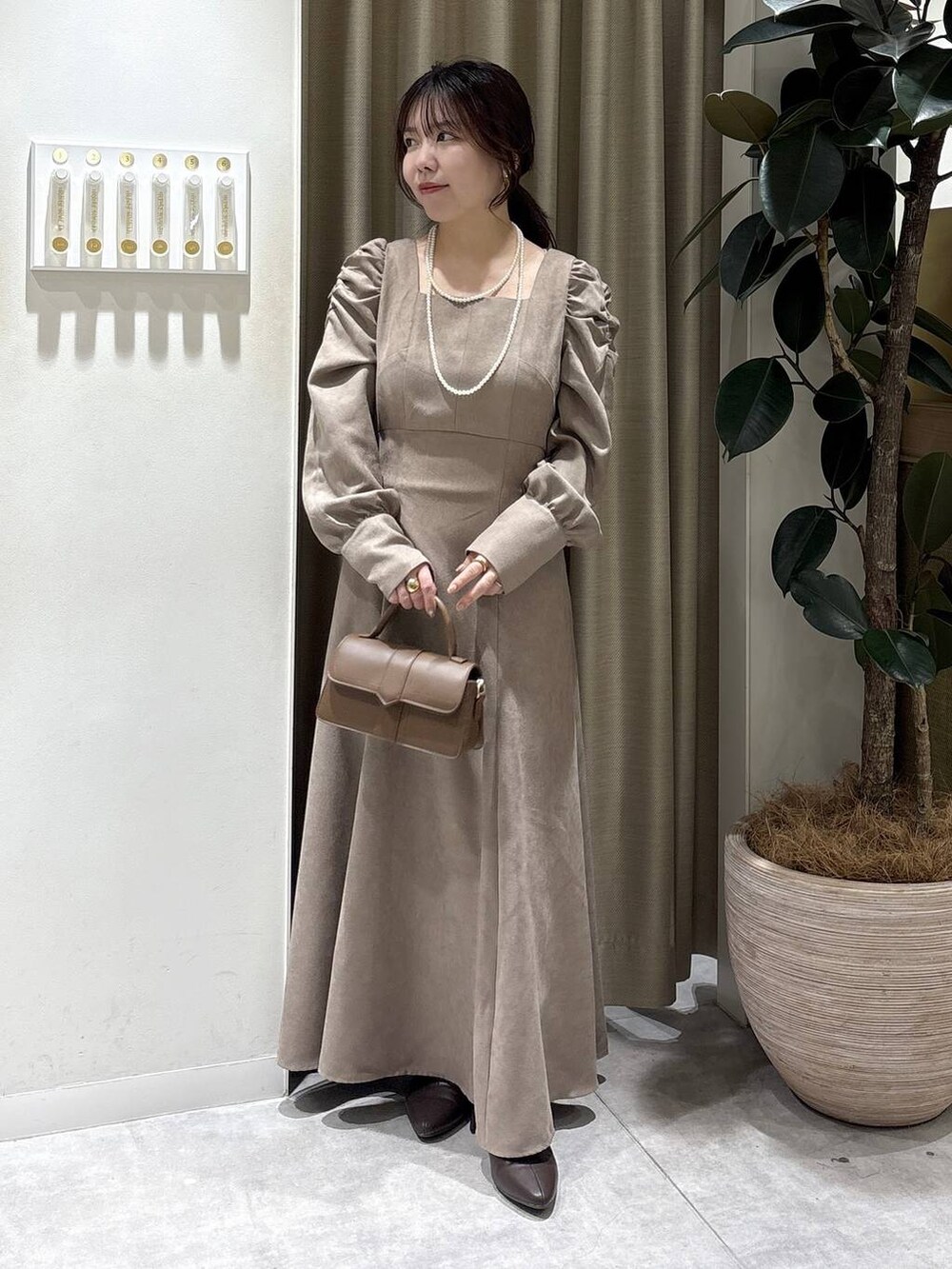 ブラウン系のブーツ、ブラウン系のショルダーバッグ、ベージュ系のワンピースを着用したレディースの冬コーディネートの4枚目の写真