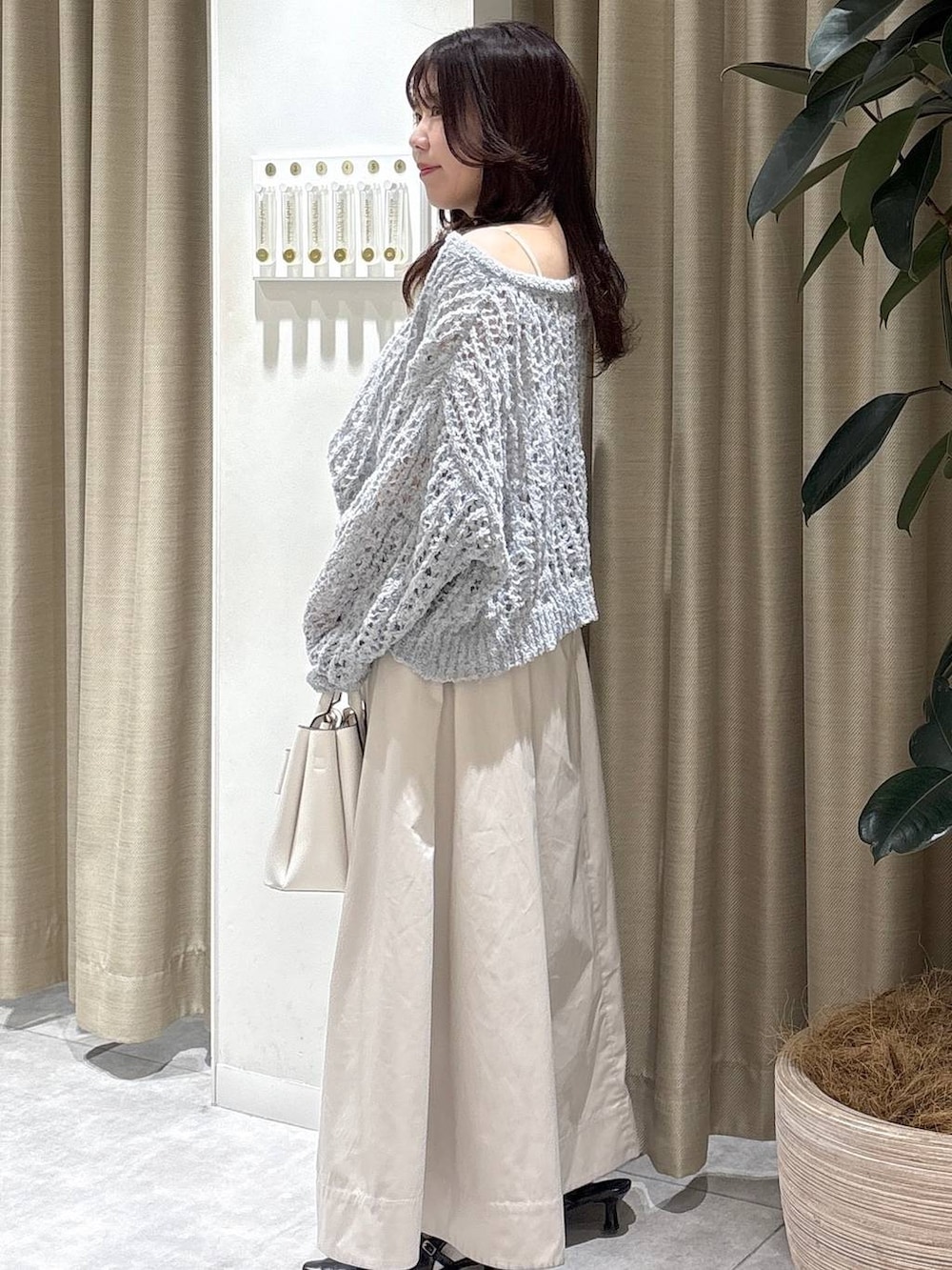 ホワイト系のショルダーバッグ、ブラック系のサンダル、ベージュ系のスカートを着用したレディースの冬コーディネートの3枚目の写真