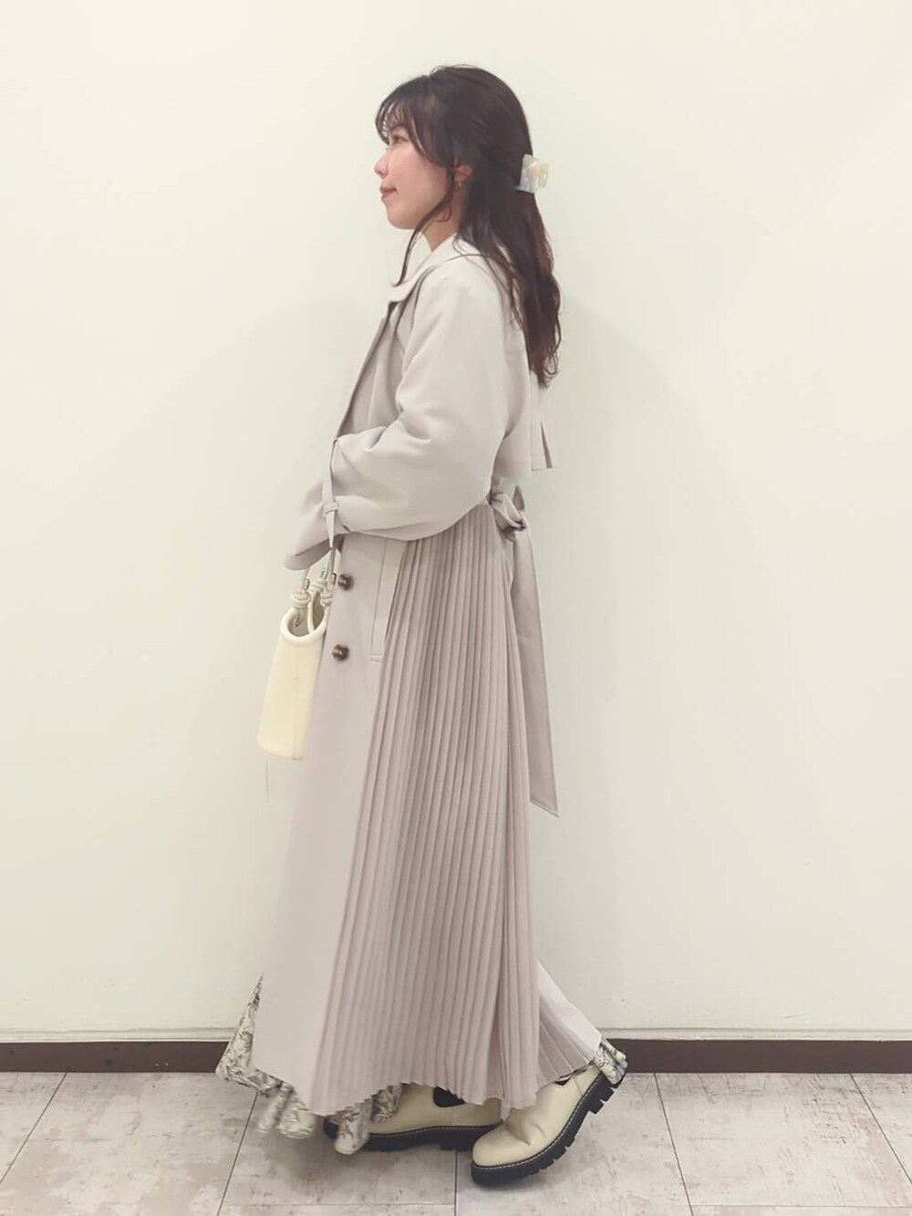 グレー系のニット/セーター、ホワイト系のハンドバッグ、ホワイト系のブーツを着用したレディースの春コーディネートの3枚目の写真
