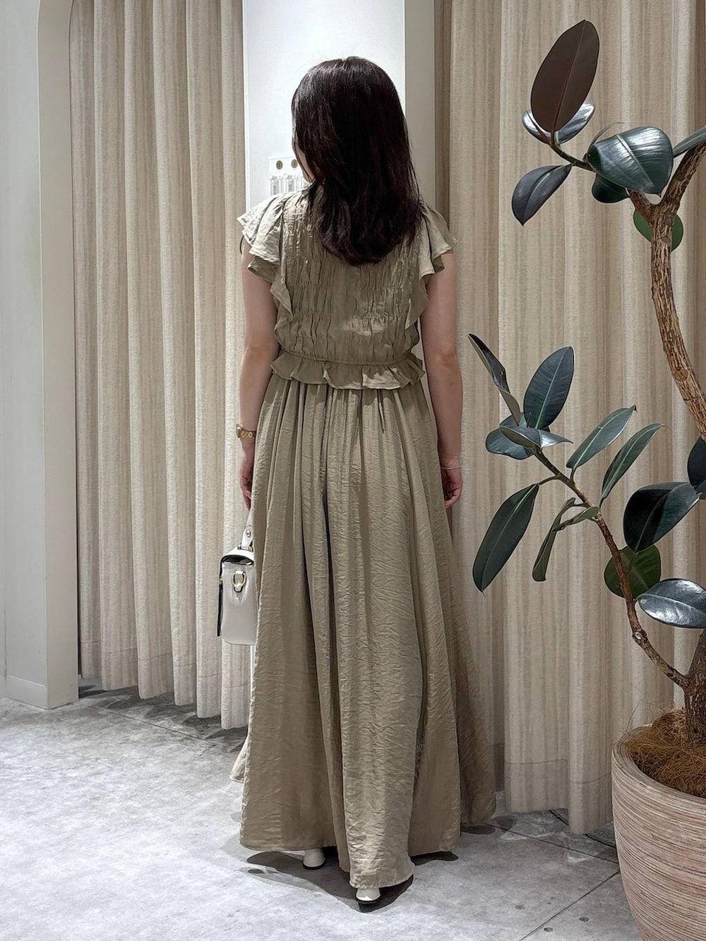 ベージュ系のワンピース、ホワイト系のショルダーバッグ、ゴールド系のネックレスを着用したレディースの夏コーディネートの3枚目の写真